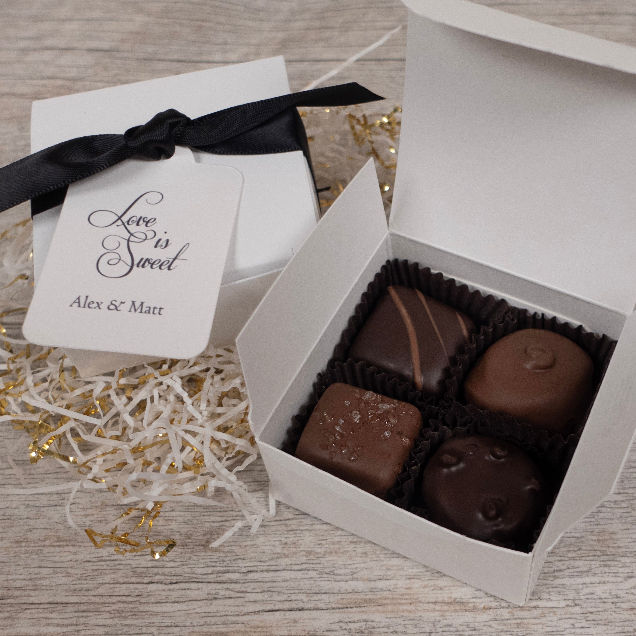 Box of chocolates with a 'Love is Sweet' hang tag on a wooden surface