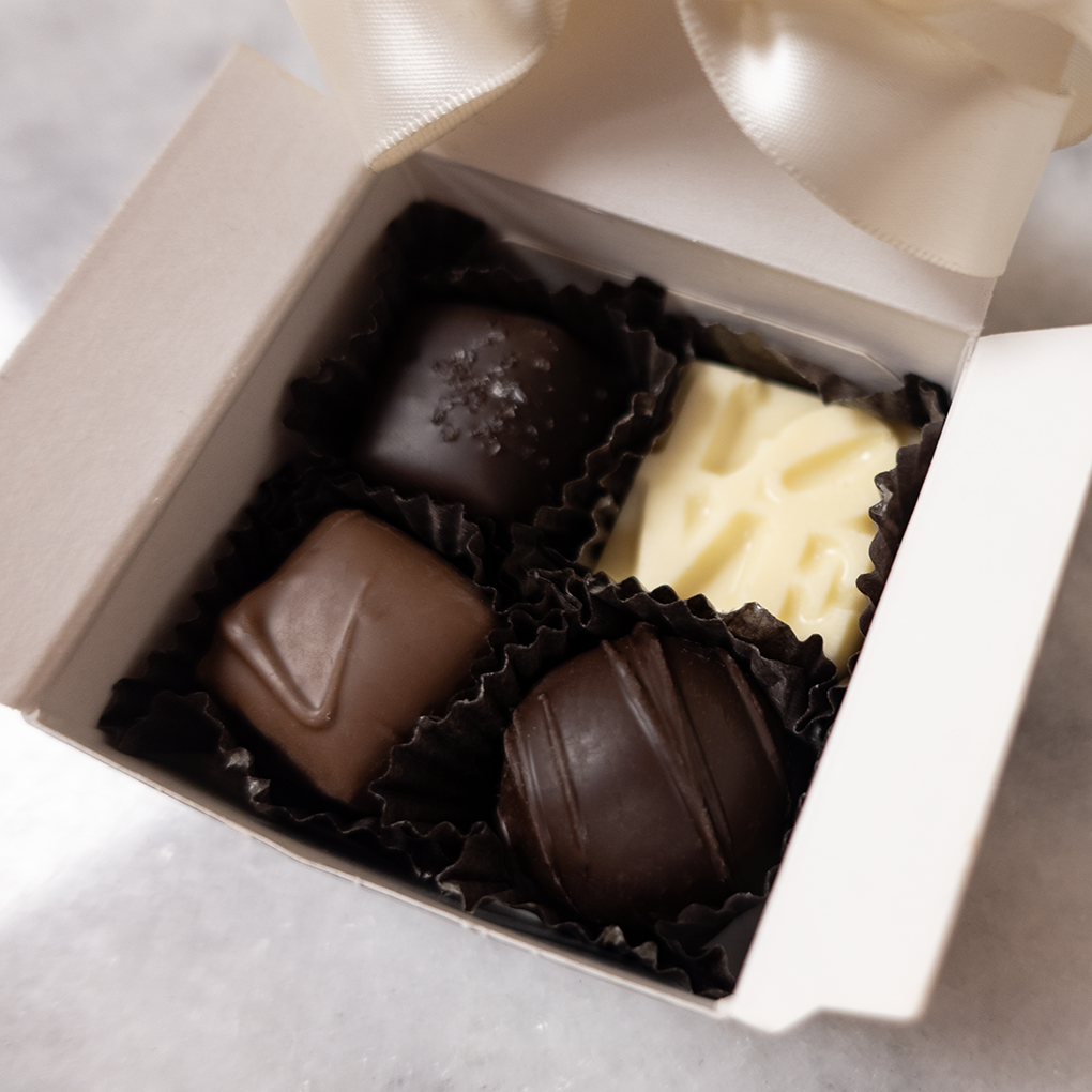 detail shot showing a dark chocolate sea salt caramel, white chocolate solid LOVE, milk chocolate vanilla caramel, and a dark chocolate truffle.