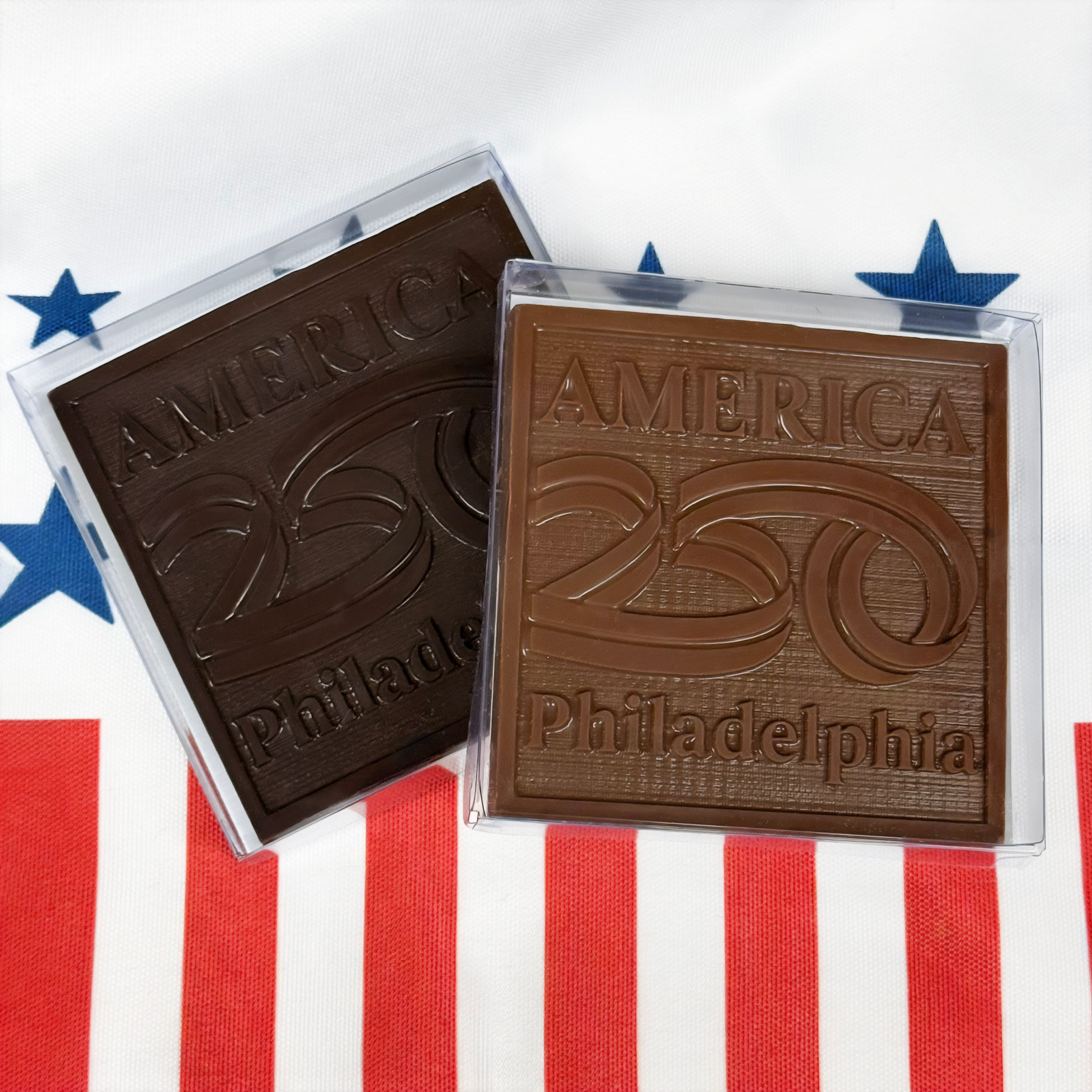 Two chocolate bars with 'America 250 Philadelphia' text on a red, white, and blue striped background.