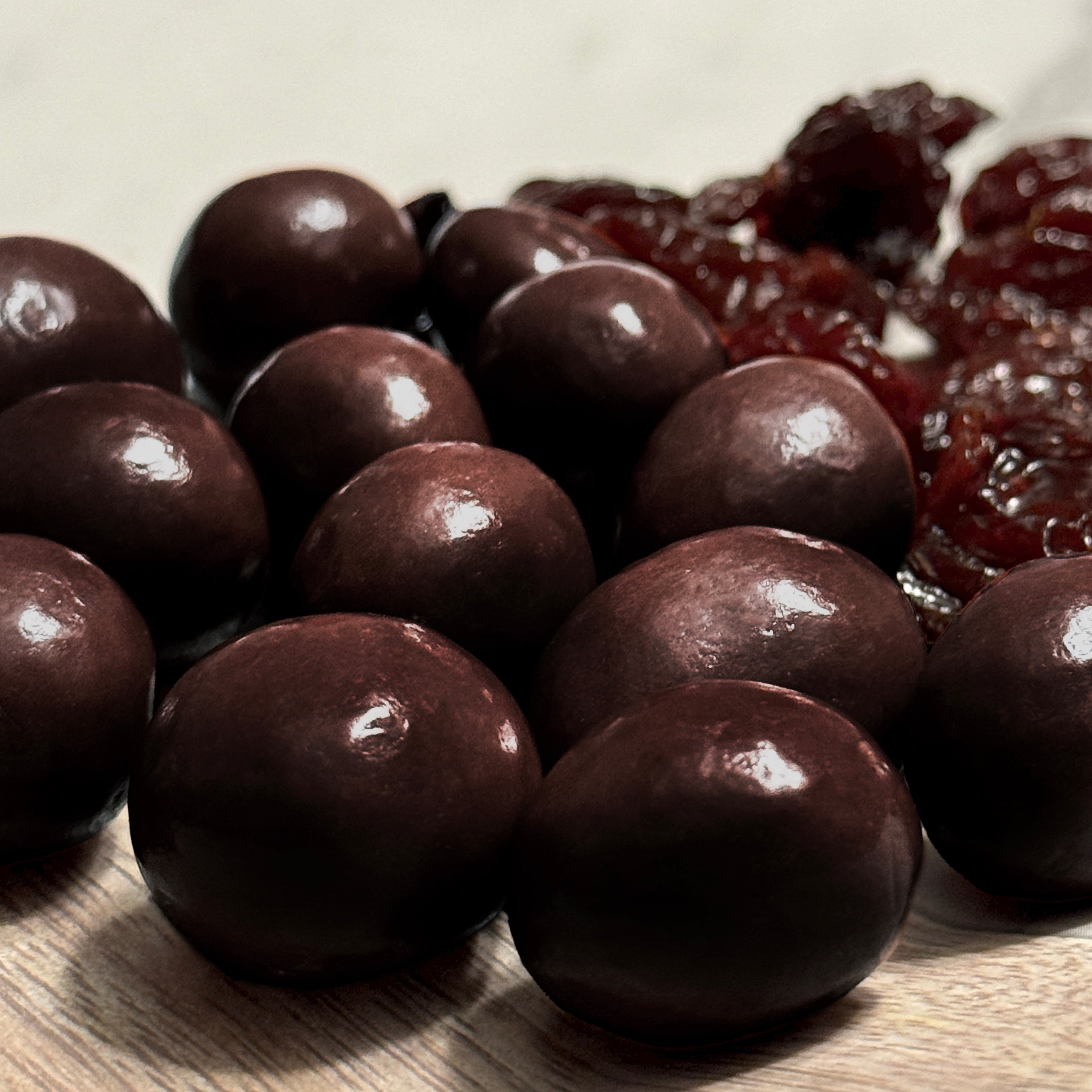 Close-up of dark chocolate cranberries and dried cranberries on a wooden surface
