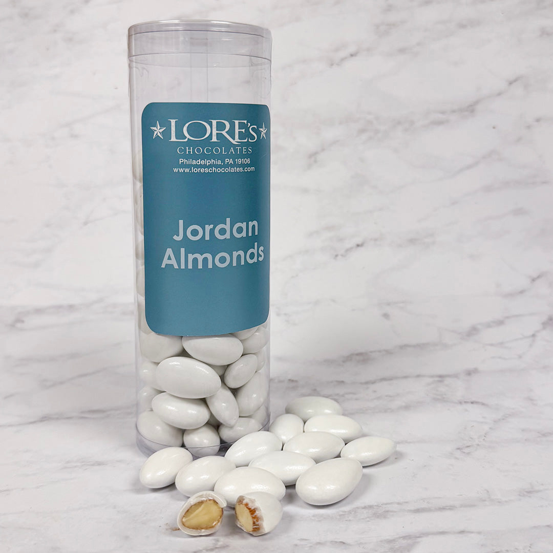 Clear cylindrical container of Jordan Almonds with a blue label on a marble surface