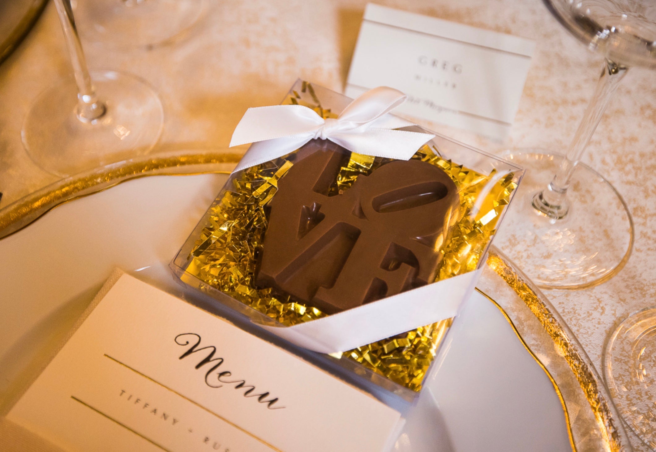 LOVE chocolate favor on a gold edged play on a wedding table with place setting and menu