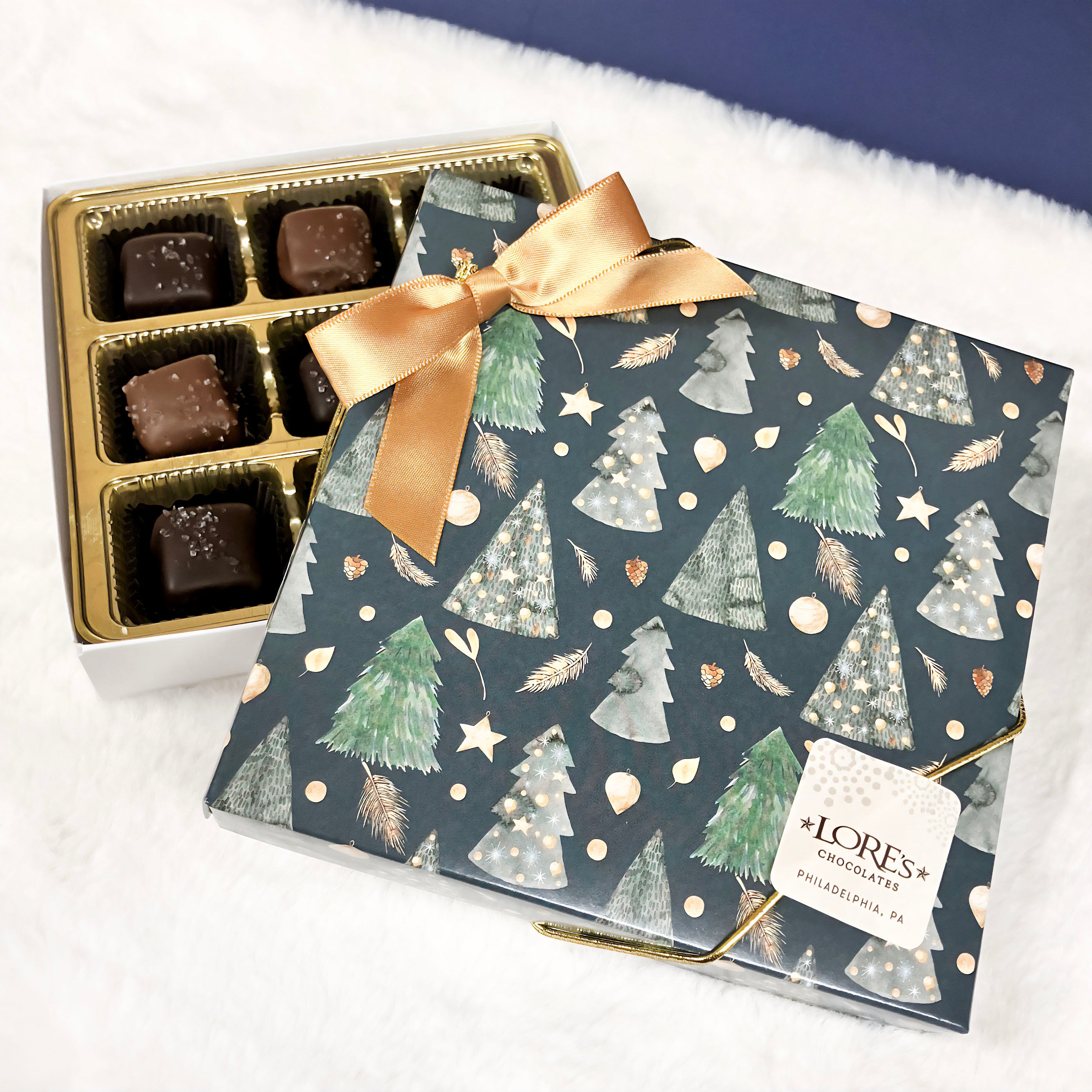 Chocolate box with a gold bow and Christmas tree pattern on a white background