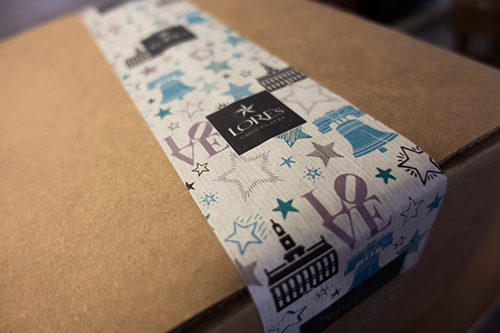 Close up of a shipping cardboard box with Lore's Chocolates tape on top.
