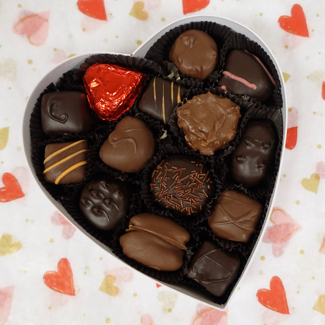 Heart-shaped box of assorted chocolates on a heart-patterned background