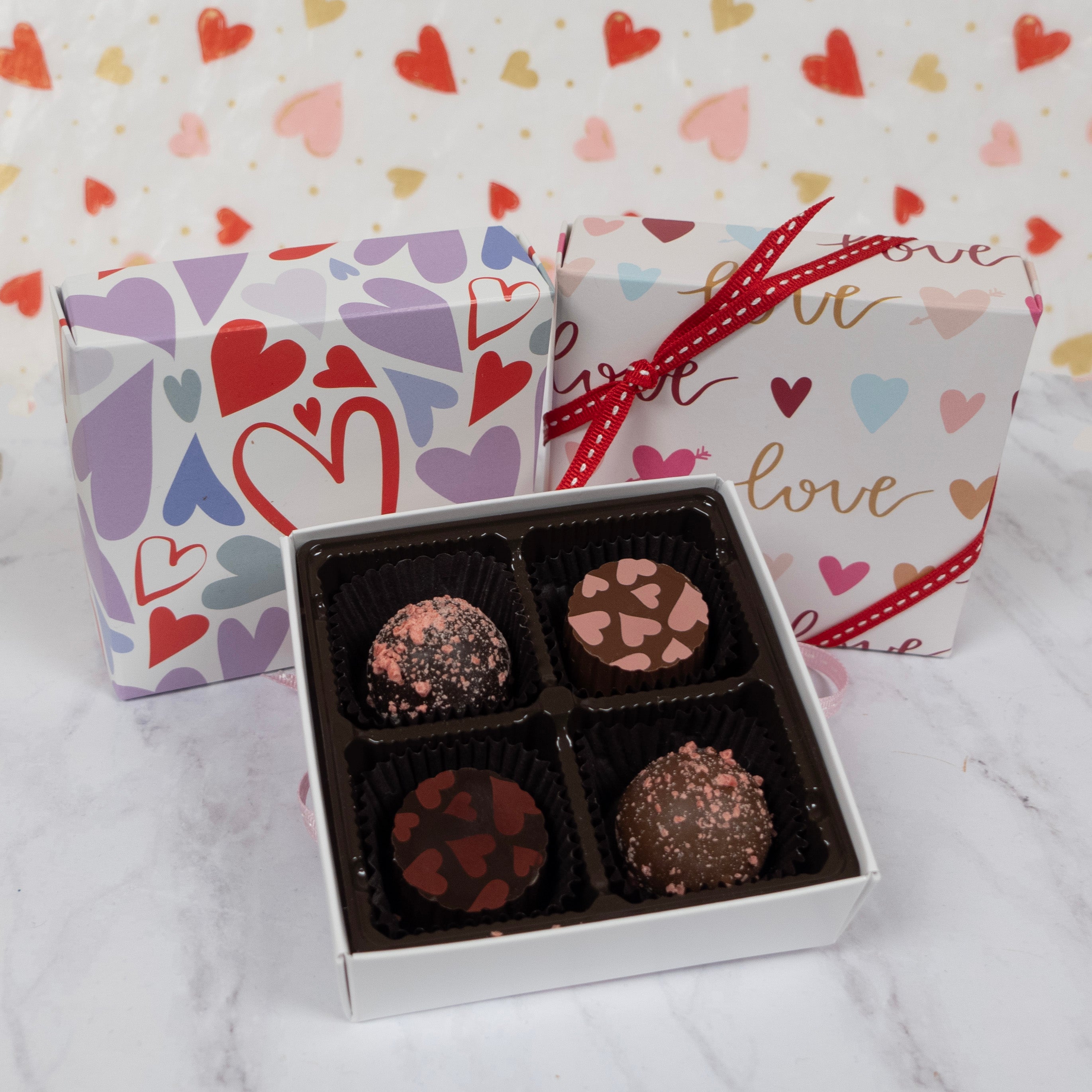 Box of chocolates with decorative gift boxes on a heart-patterned background
