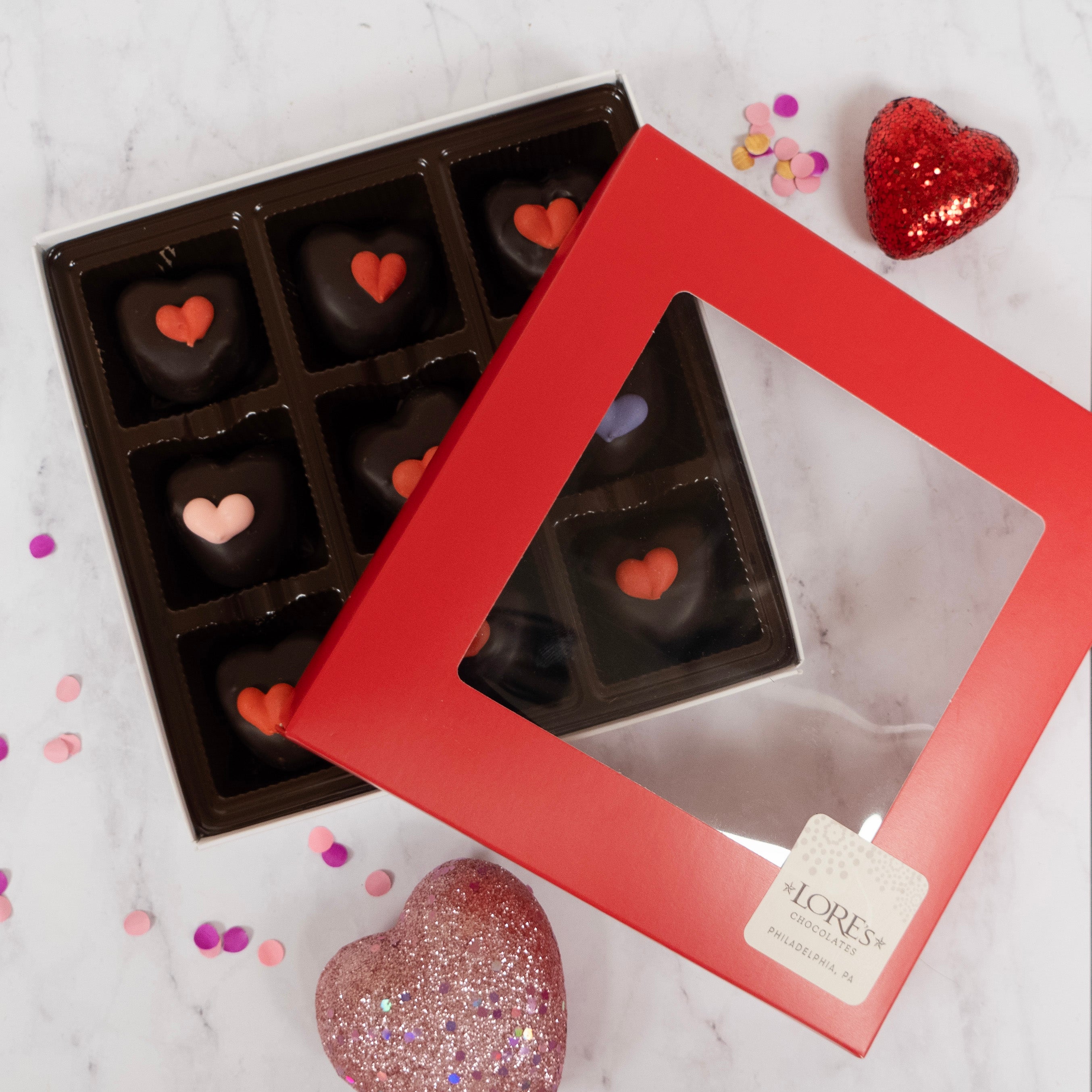 Chocolate hearts in a box with a red frame on a marble surface