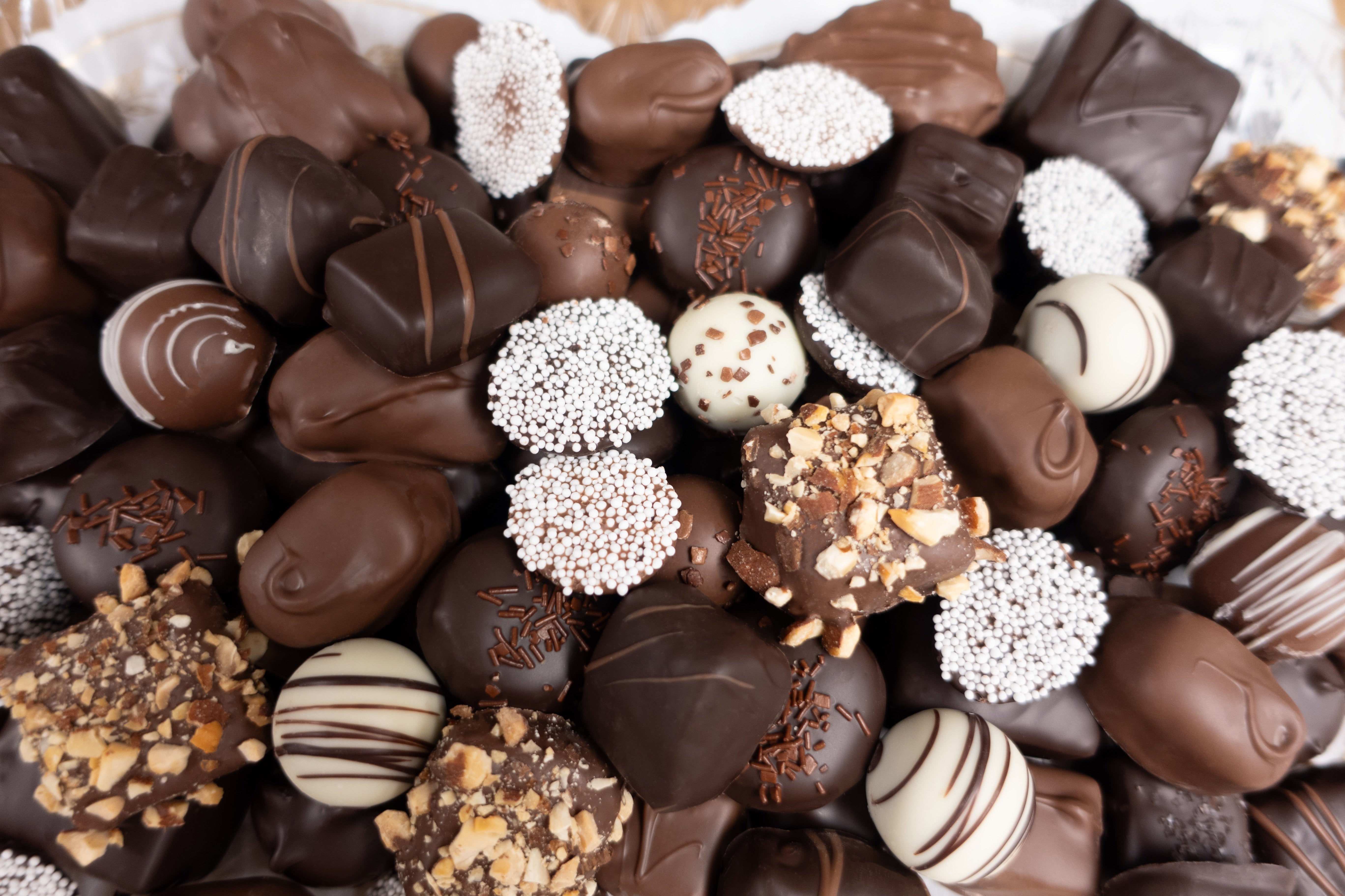 Assorted chocolates &  truffles with various toppings on a white background