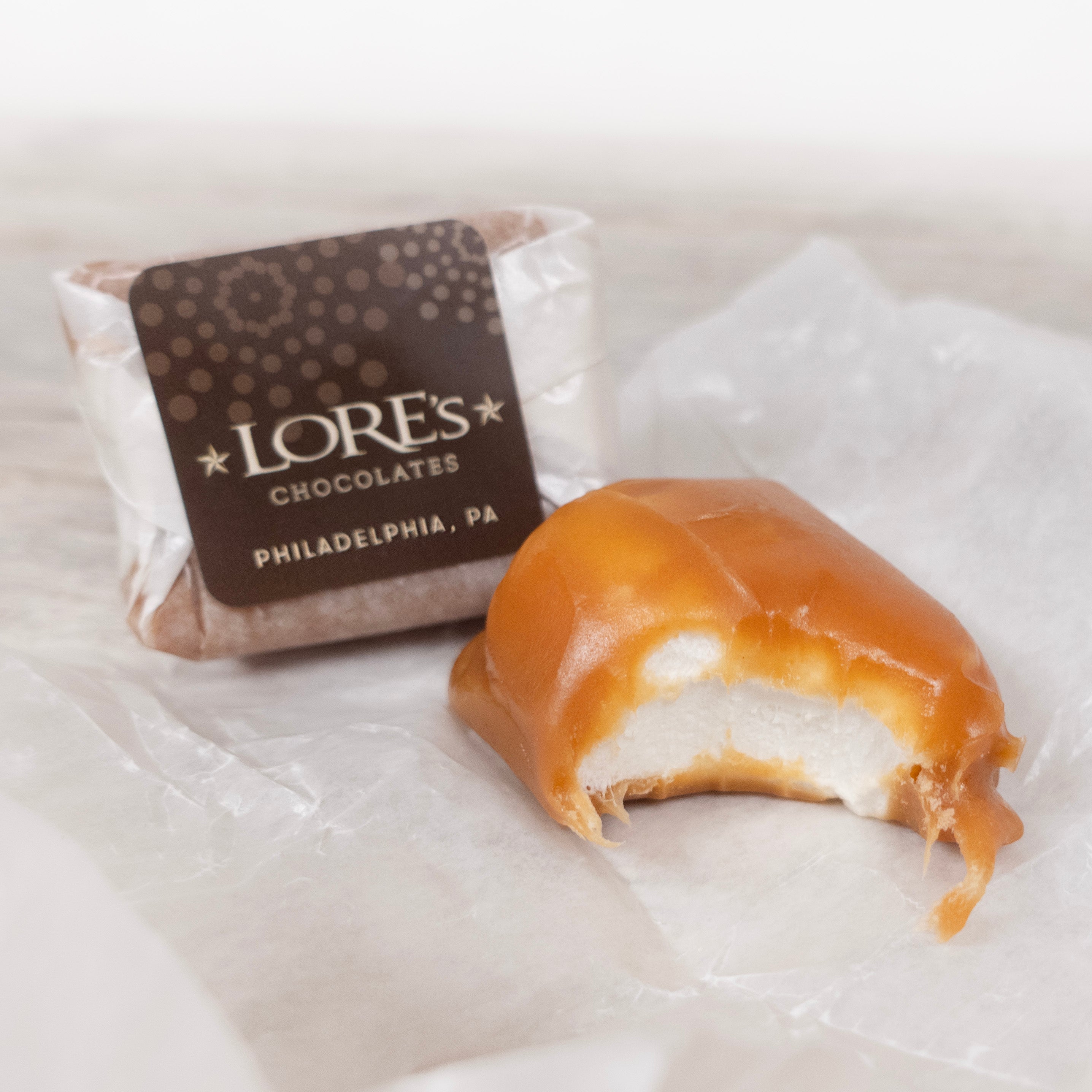 Lore's Chocolates of Philadelphia, PA on the wrapper of the handmade caramellos - with a detail shot of a caramello with a bite taken out. inside is handmade marshamllow.