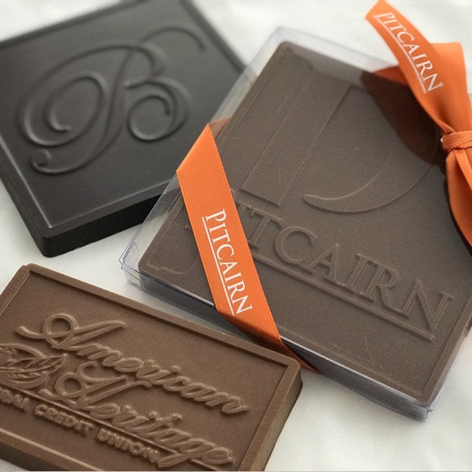 three custom chocolate bars showing the molded logo of three different businesses.