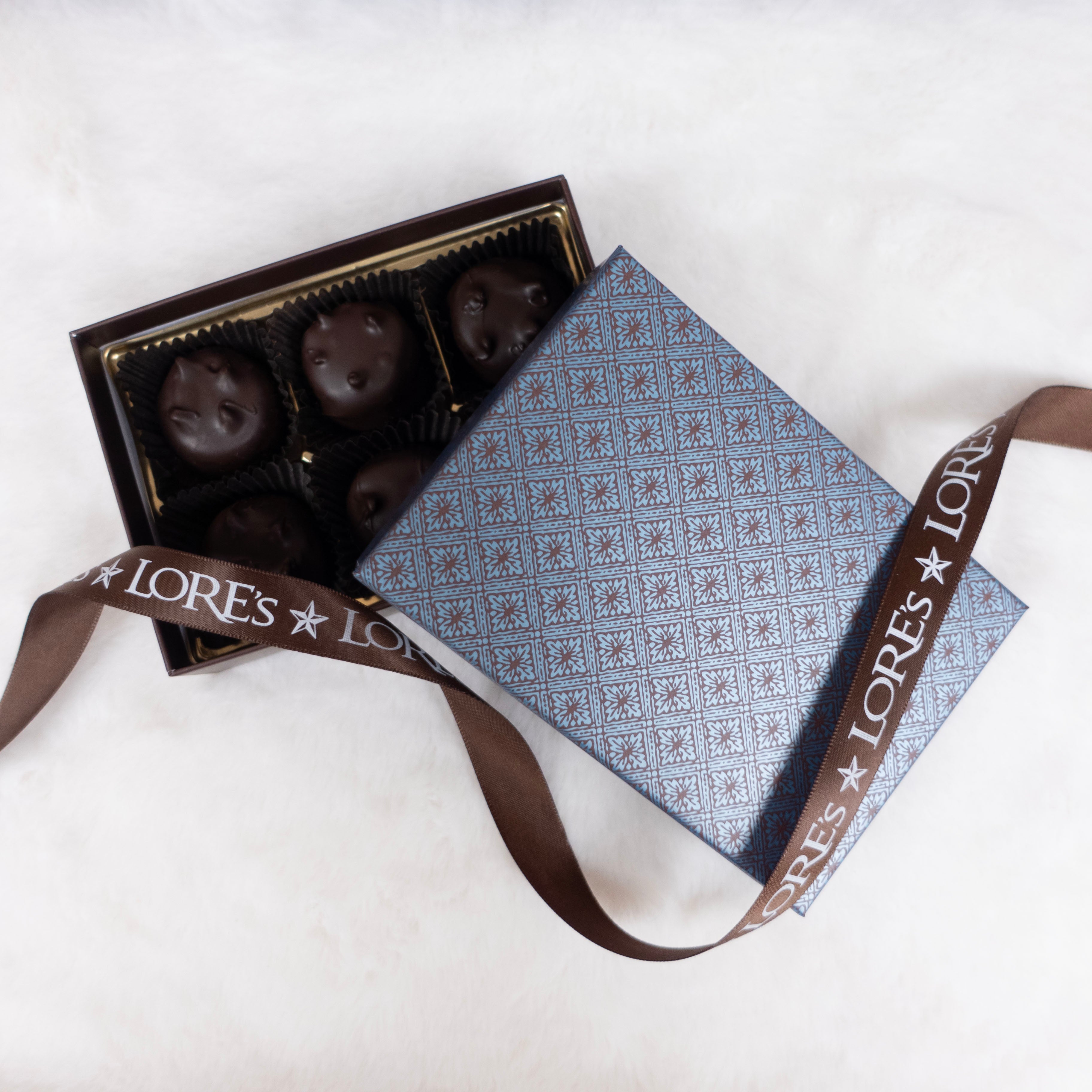 Box of chocolates with a patterned lid and ribbon on a white background