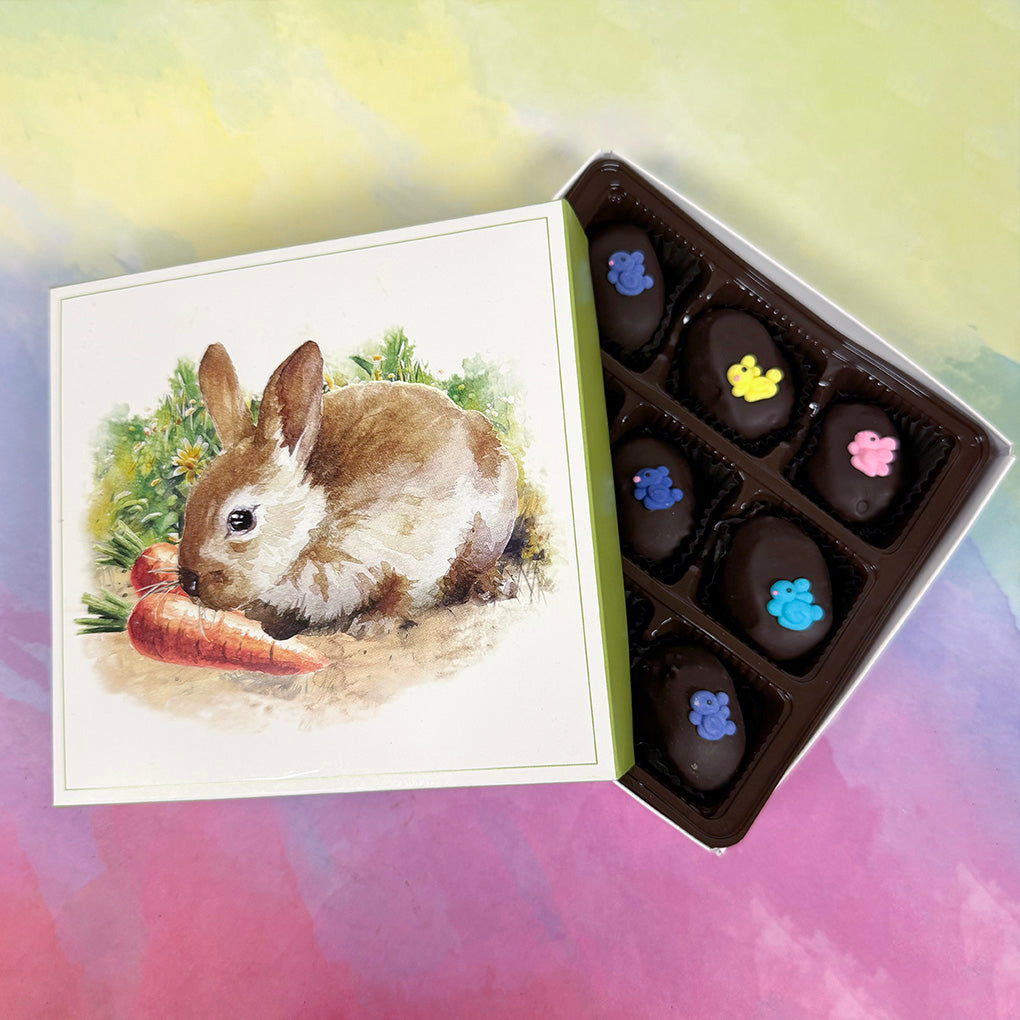 Box of Easter dark chocolates with decorative elements resembling colorful bunnies with a box with a rabbit and carrot illustration.