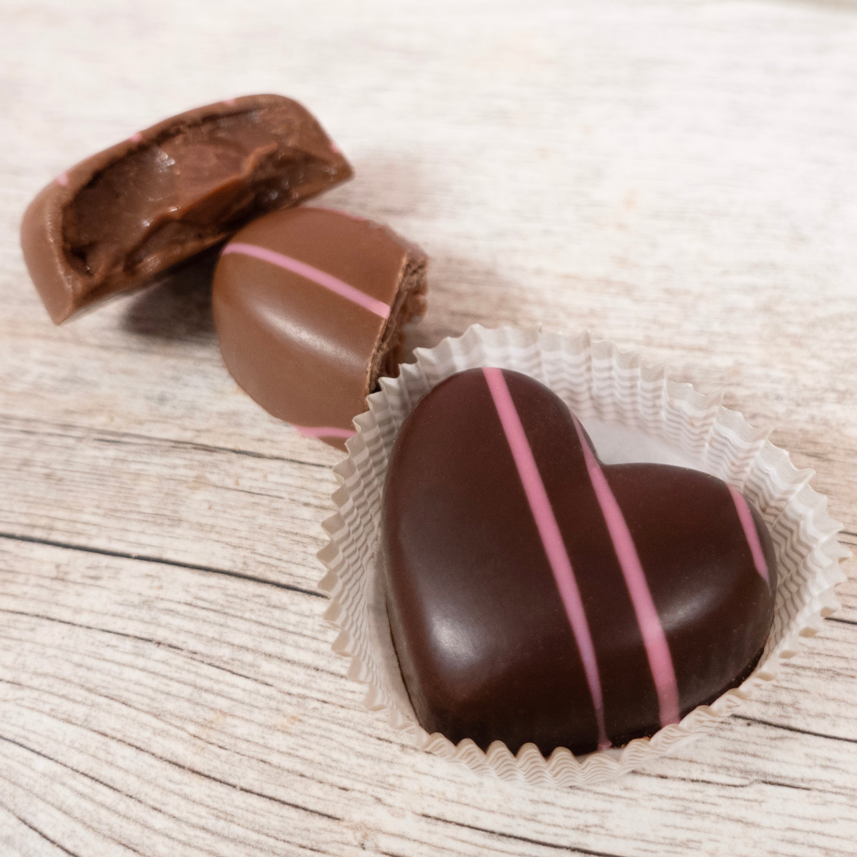 heart-shaped truffles, one dark chocolate, and one milk chocolate cut open to show chocolate ganache center
