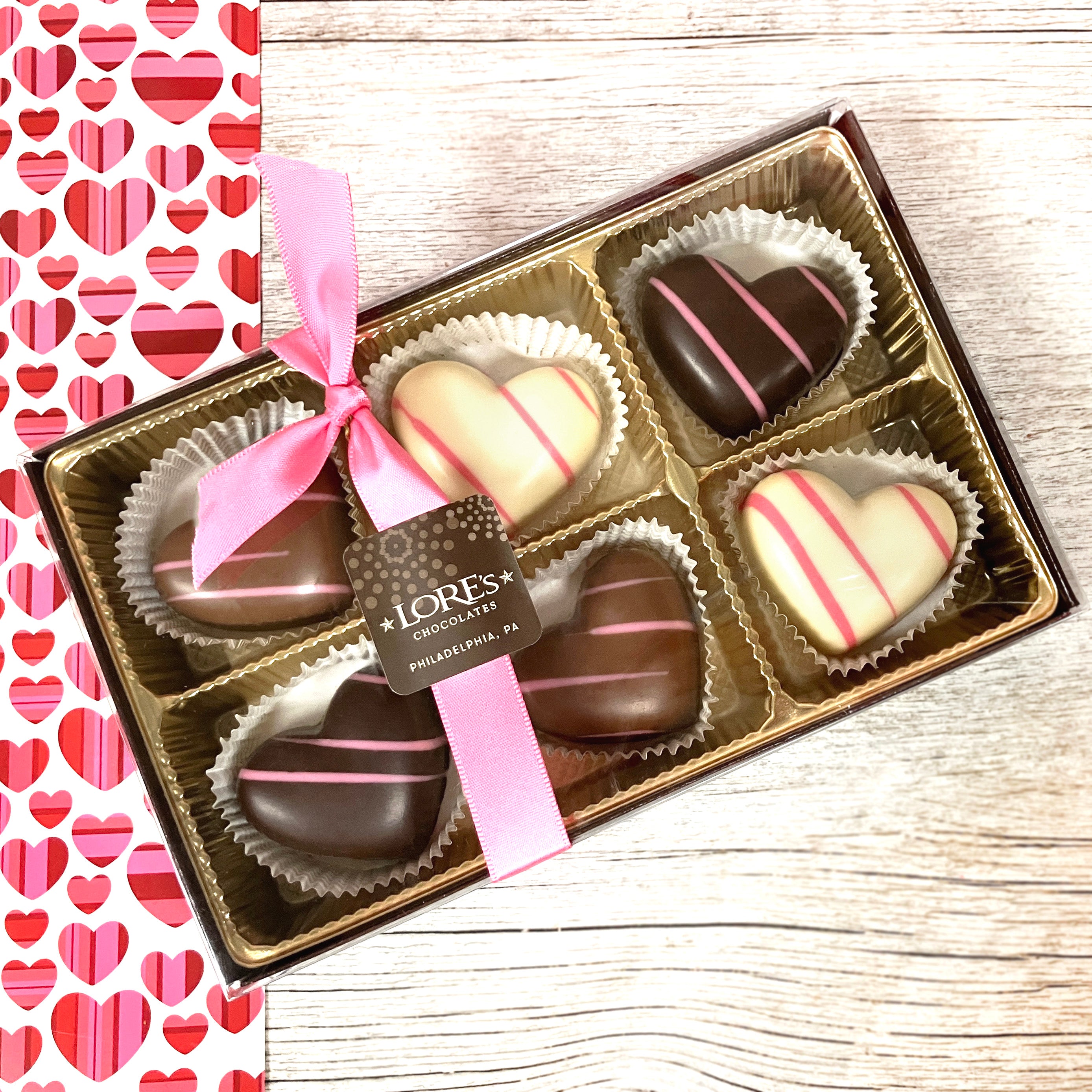 6 piece box of heart shaped truffles with pink stripes. milk dark and white chocolate available at Lore's Chocolates