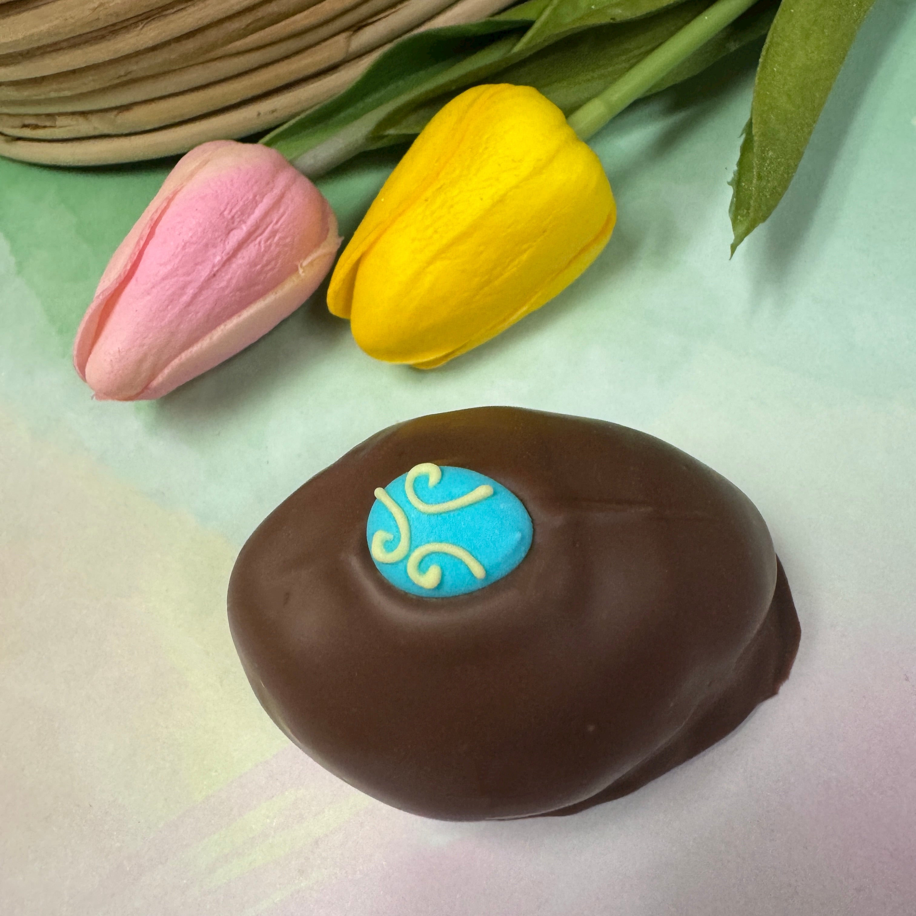 milk chocolate handmade easter egg with little blue egg sugar decoration