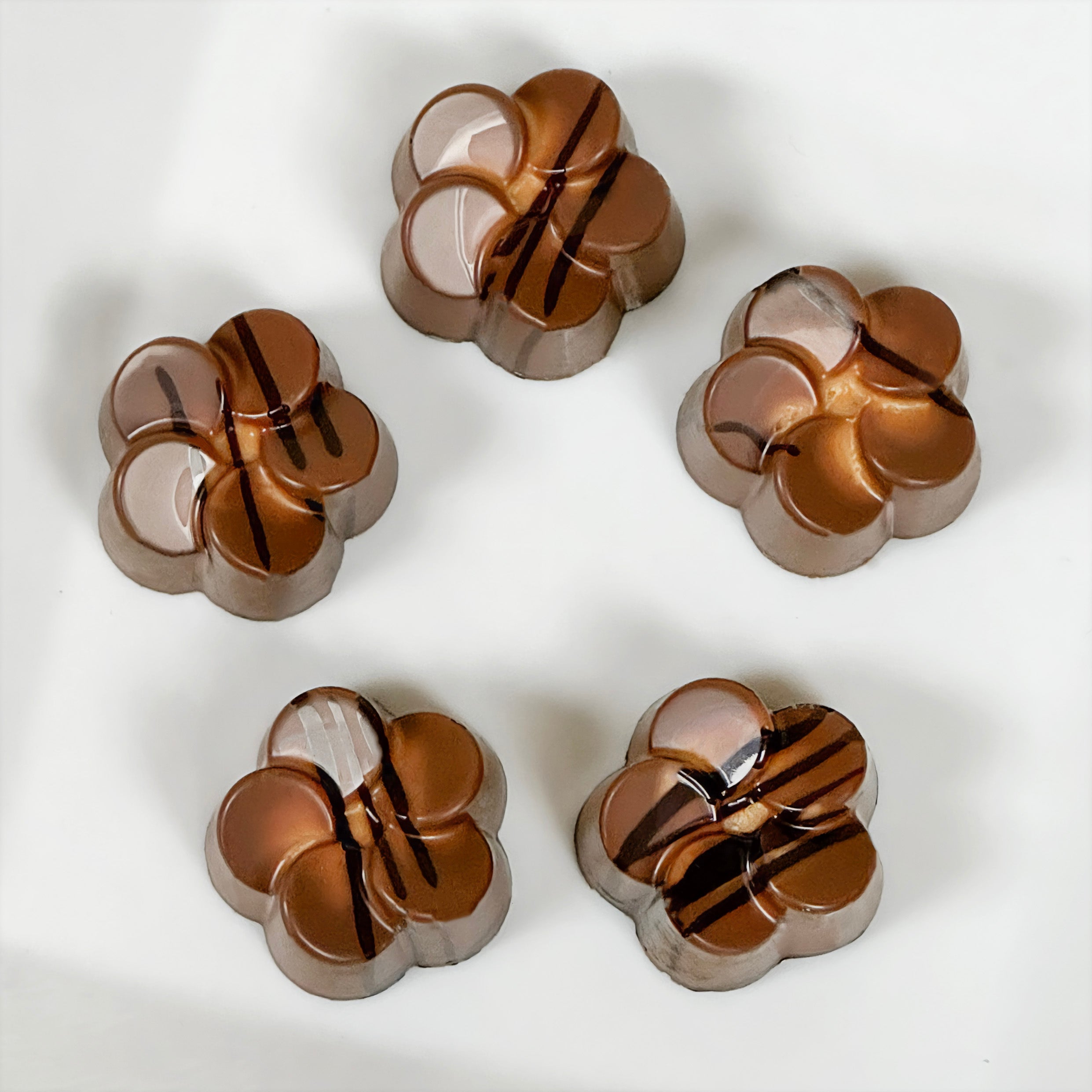 Five milk chocolate flower-shaped peanut butter meltaways on a white background - made by Lore's Chocolates in Philadelphia