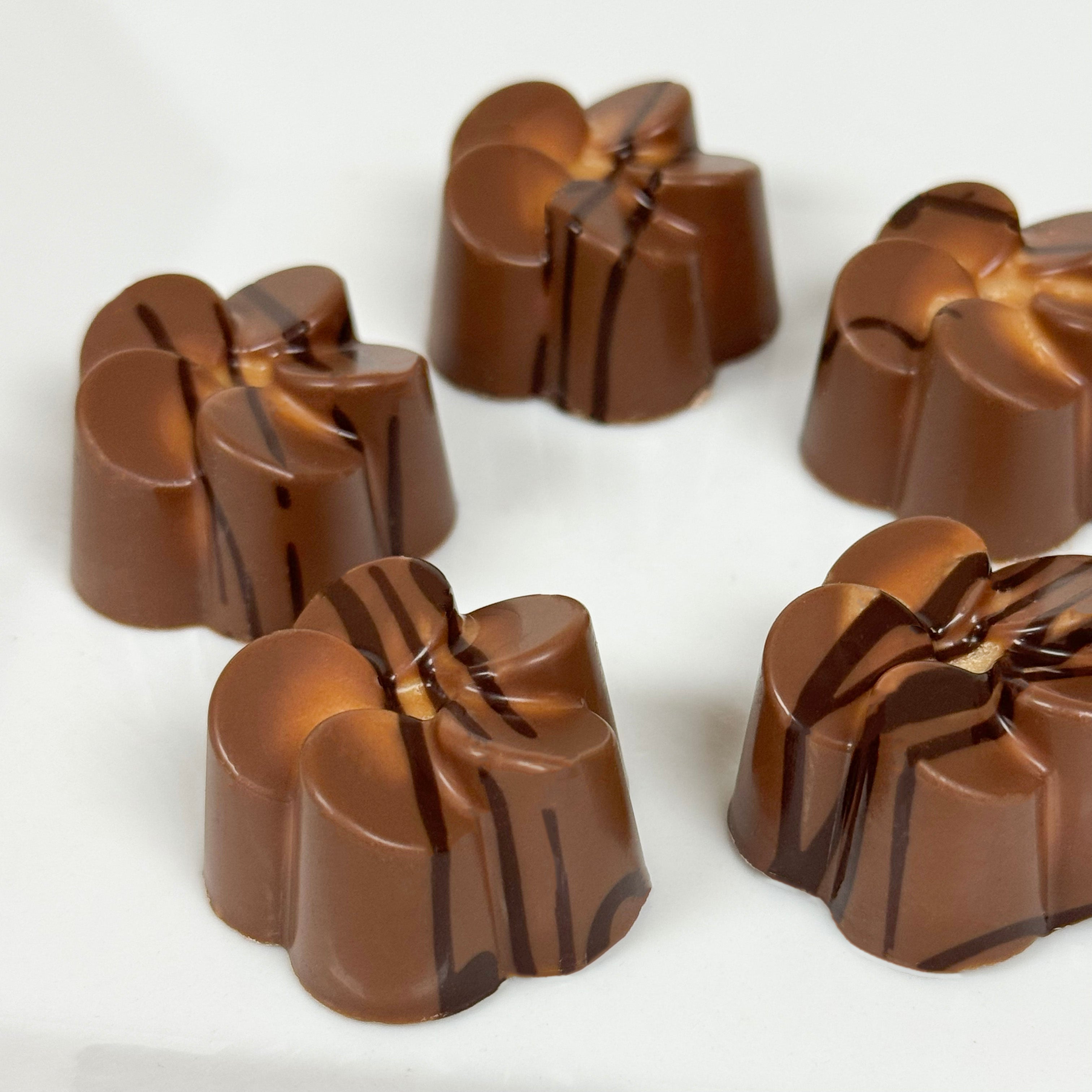 Mlk chocolate peanut butter truffles in the shape of a flower with dark chocolate drizzle on a white background - made by Lore's Chocolates in Philadelphia
