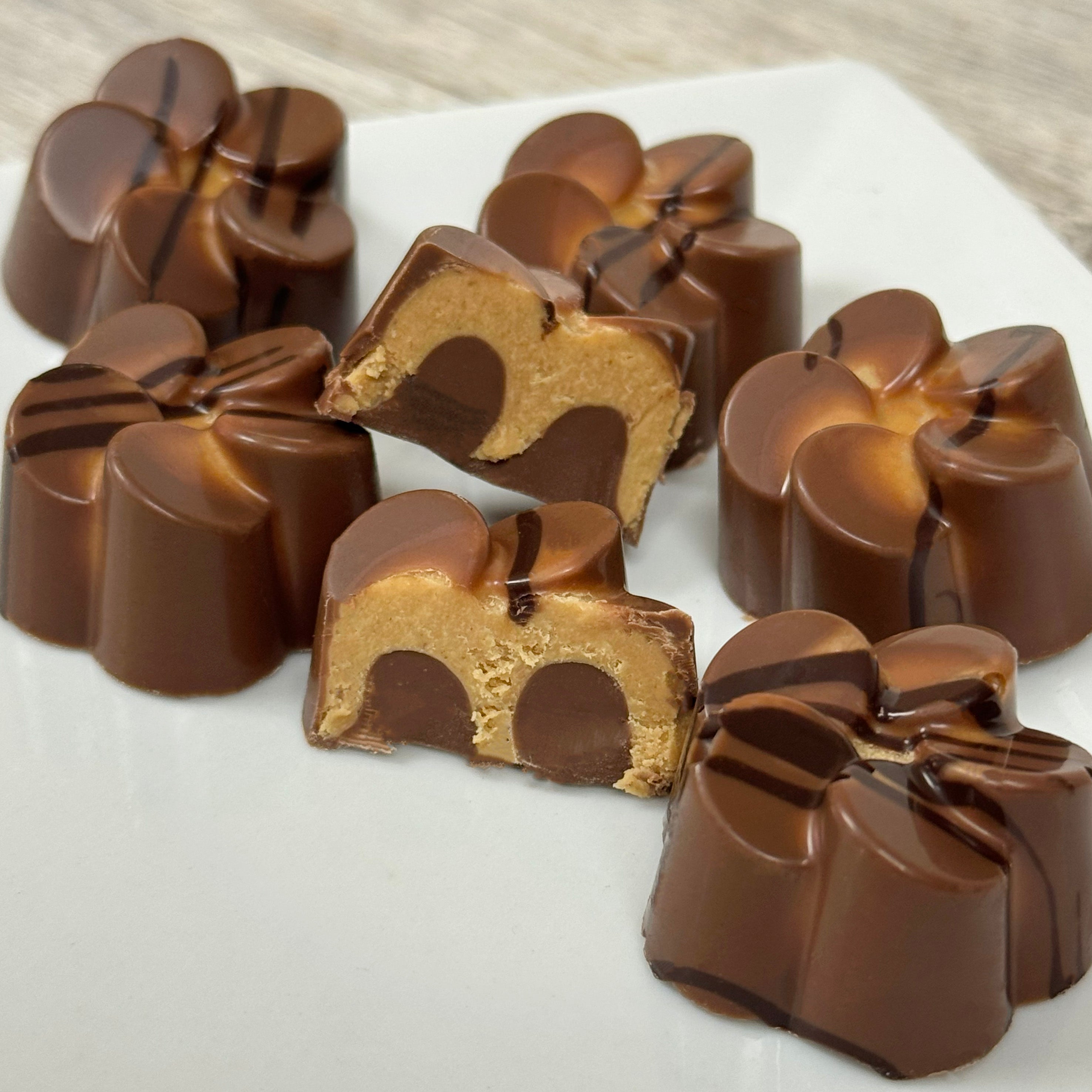 Milk chocolate candies filled with meltaway peanut butter on a white surface. Made by Lore's Chocolates in Philadelphia