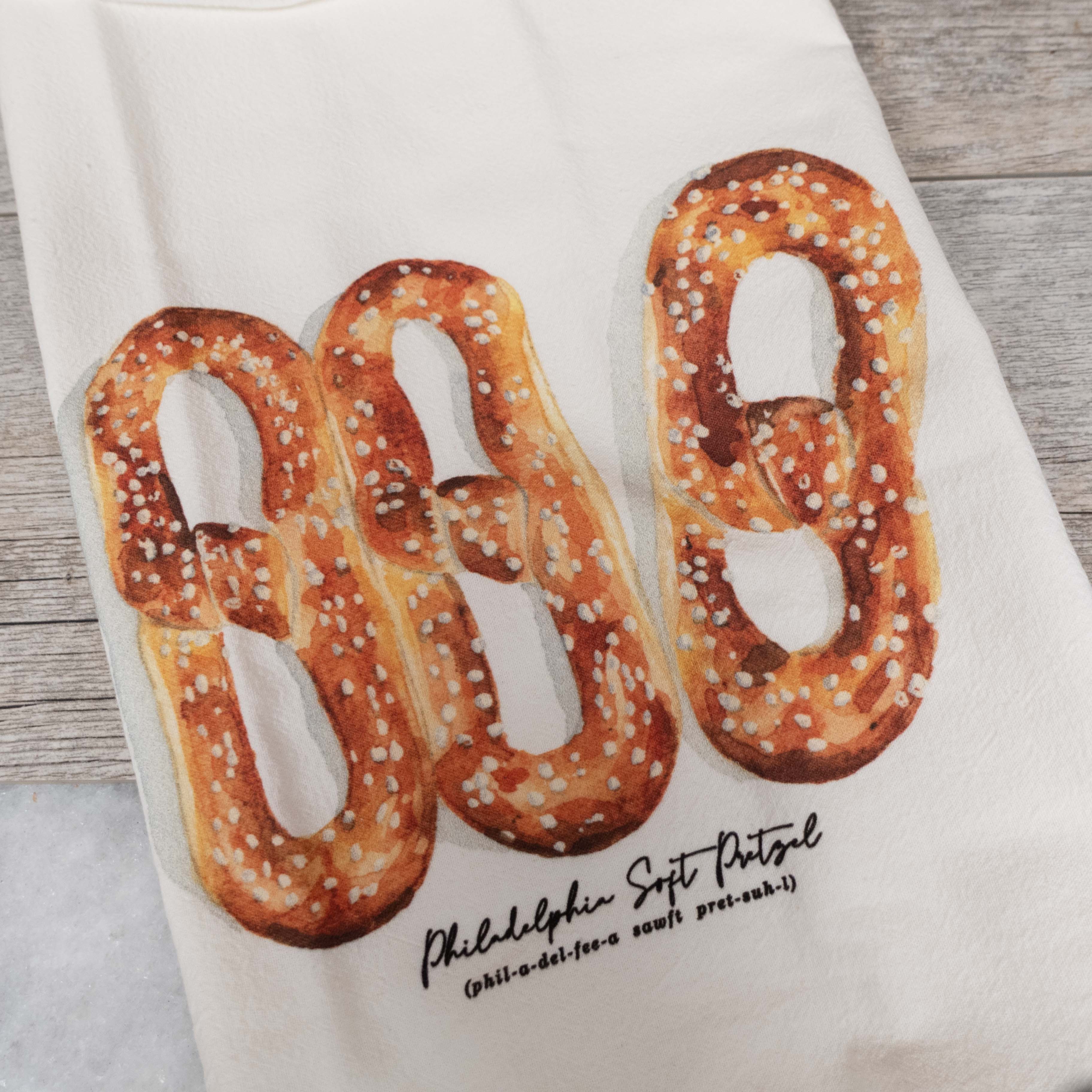 Towel with pretzel design and text on a wooden surface