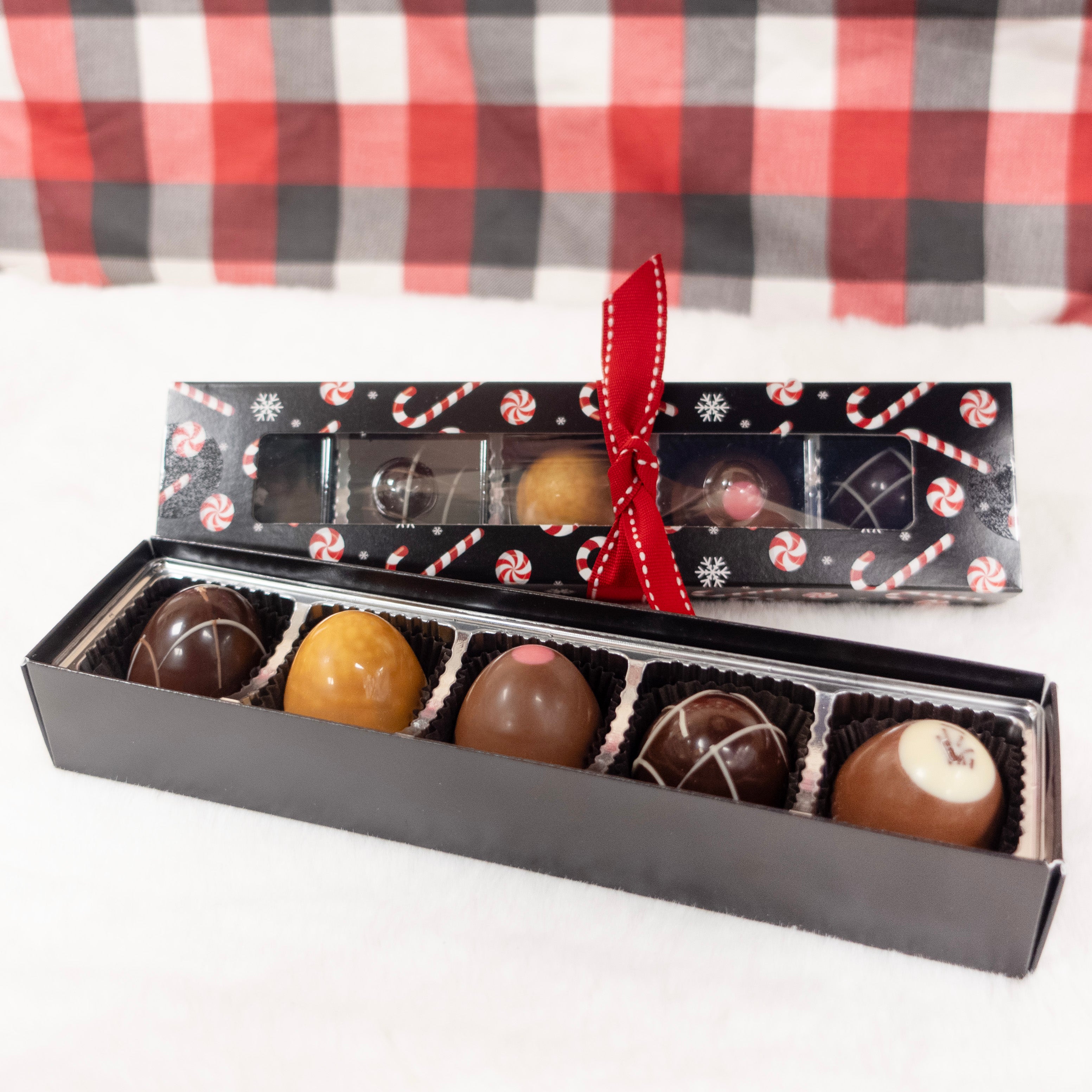 Candy Cane Box of chocolate truffles with a red ribbon on a checkered background