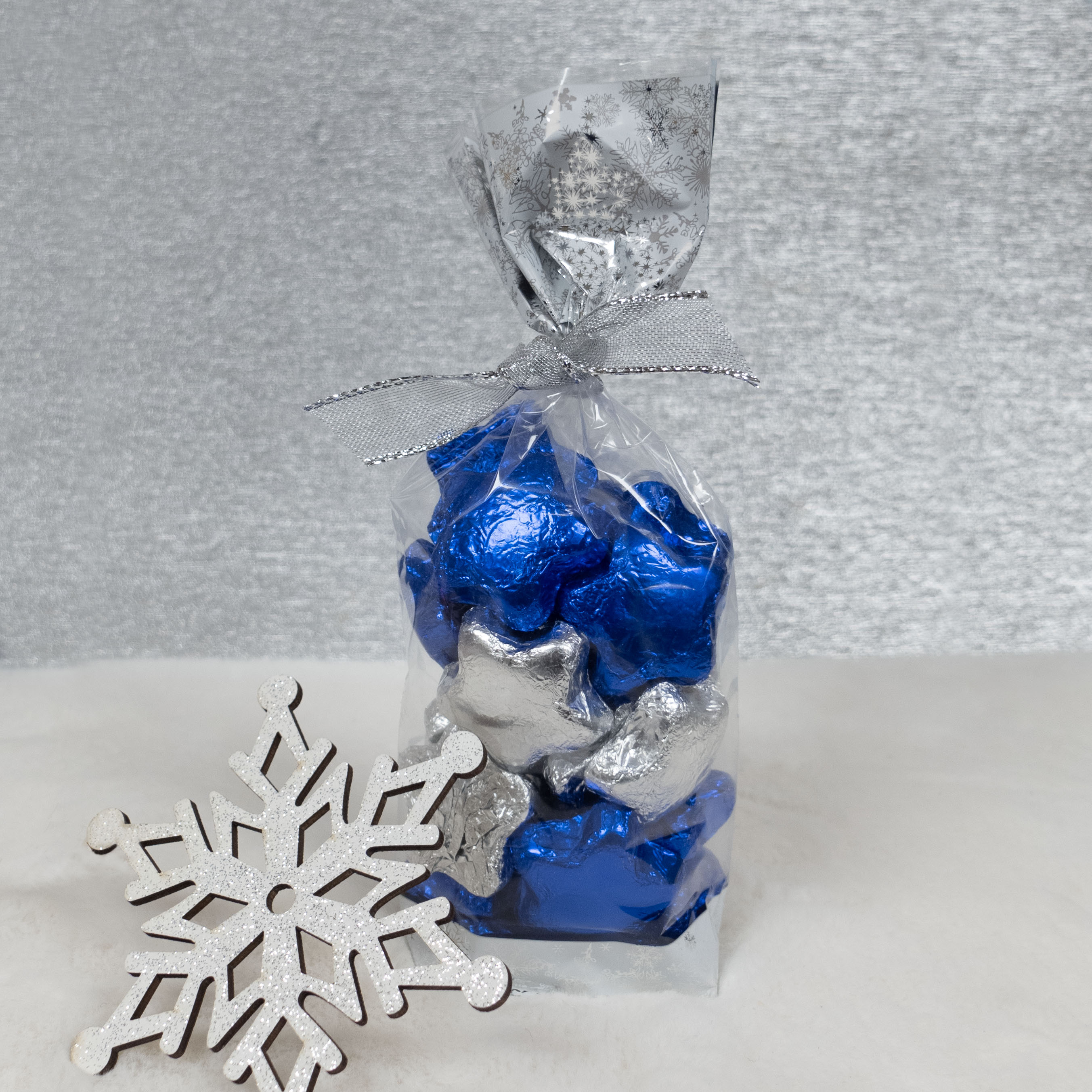 Bag of blue and silver foiled milk chocolate pieces with a decorative snowflake on a light background