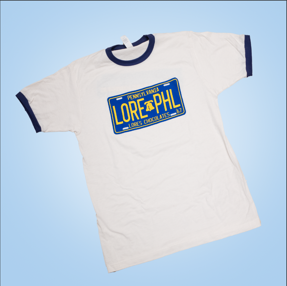 lore's chocolates vintage white t-shirt with dark blue ringer sleeves and neck. front of the shirt - PA Bicentennial License plate design "Pennsylvania, LORE (liberty bell) PHL, Lore's Chocolates, '67"