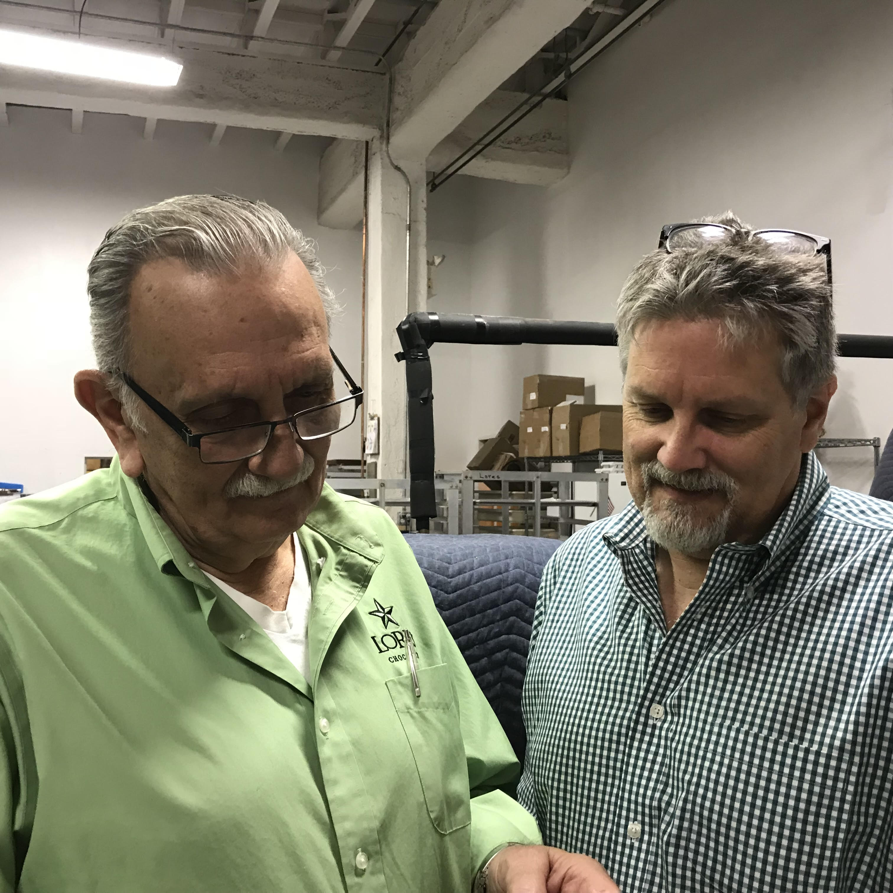 Tony Walter Sr. on the left and Tony Walter Jr. on the right. As they look down at something together in Lore's Chocolates Philadelphia Factory.