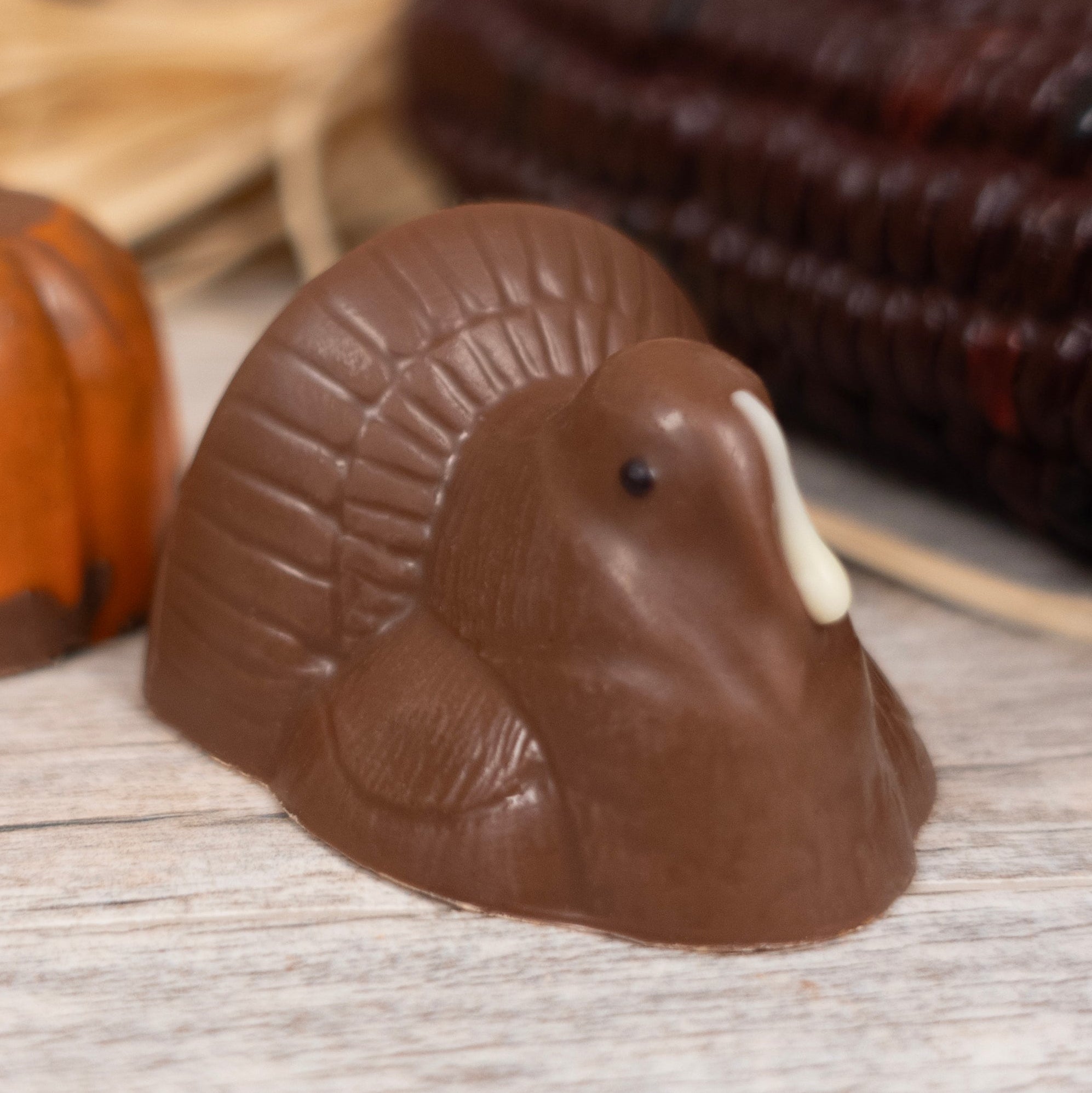 Chocolate turkey and pumpkin on a wooden surface with a rustic background.