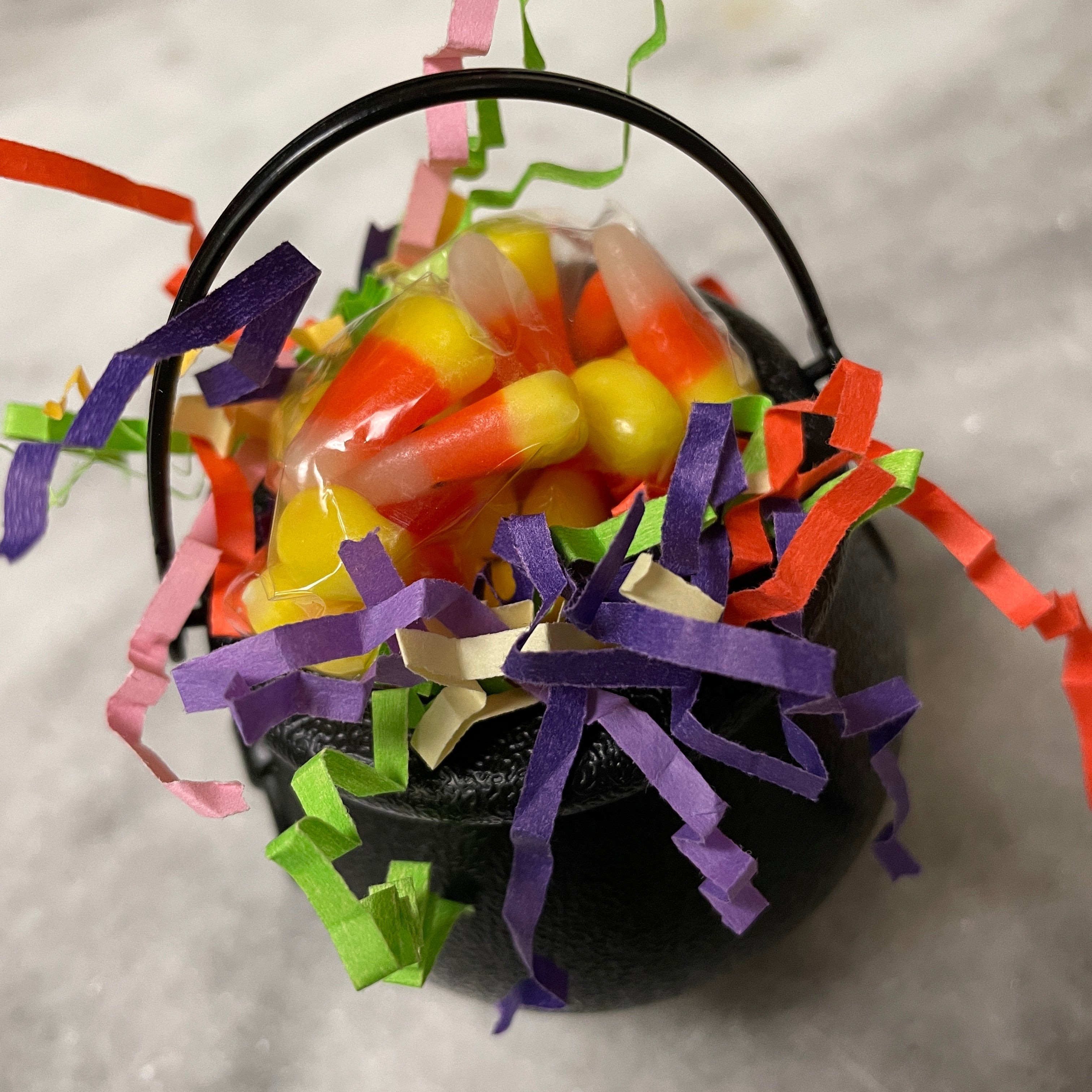 Candy corn filled black plastic cauldron with accented Halloween colored paper