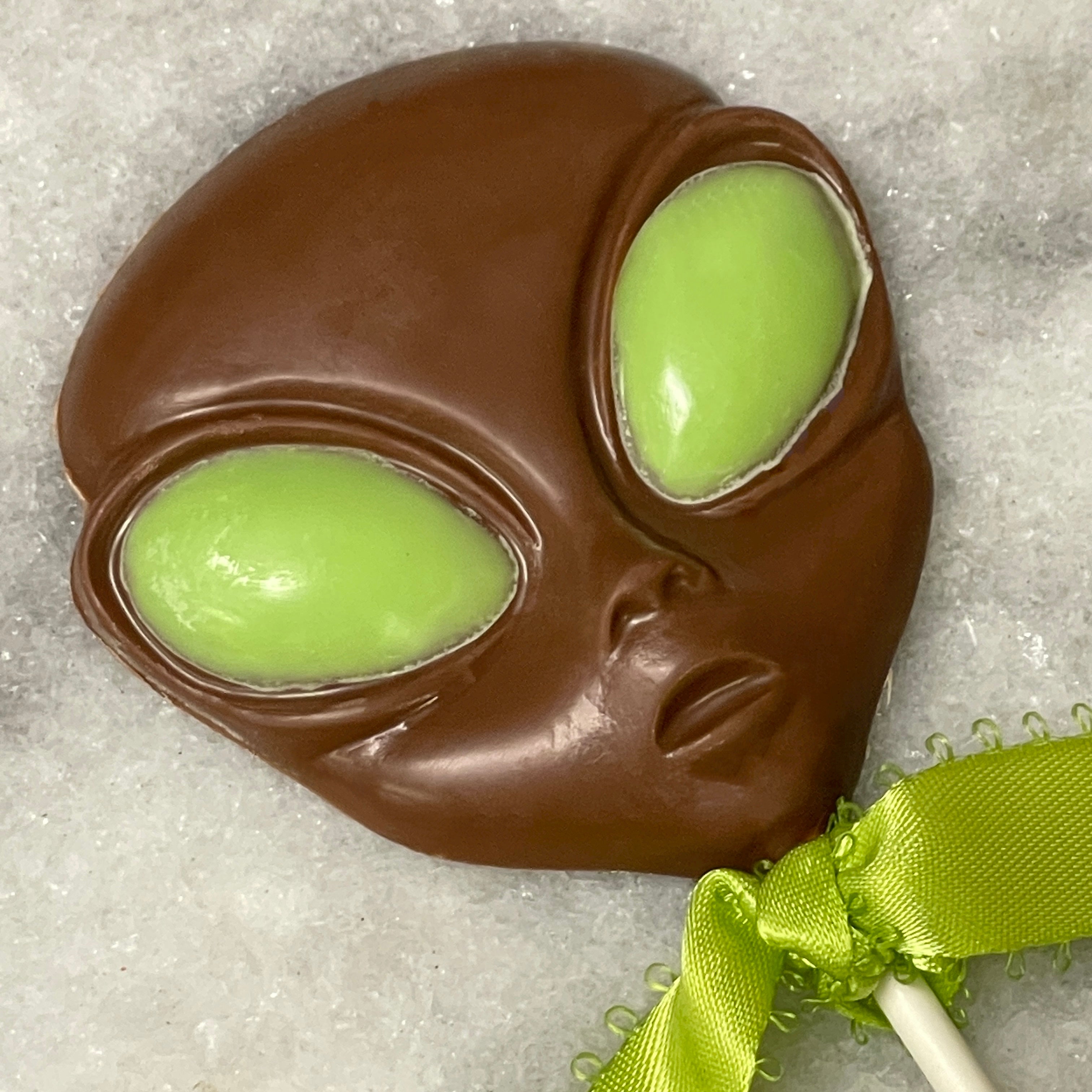 close up of the milk chocolate alien lollipop with green eyes