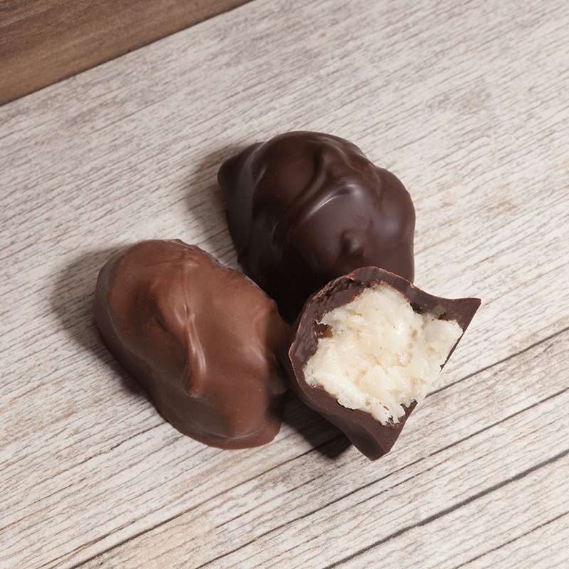 Lore's Chocolates - Coconut Cream, chocolates made in philadelphia, one cut open to show the creamy fresh coconut filling. on a wooden surface