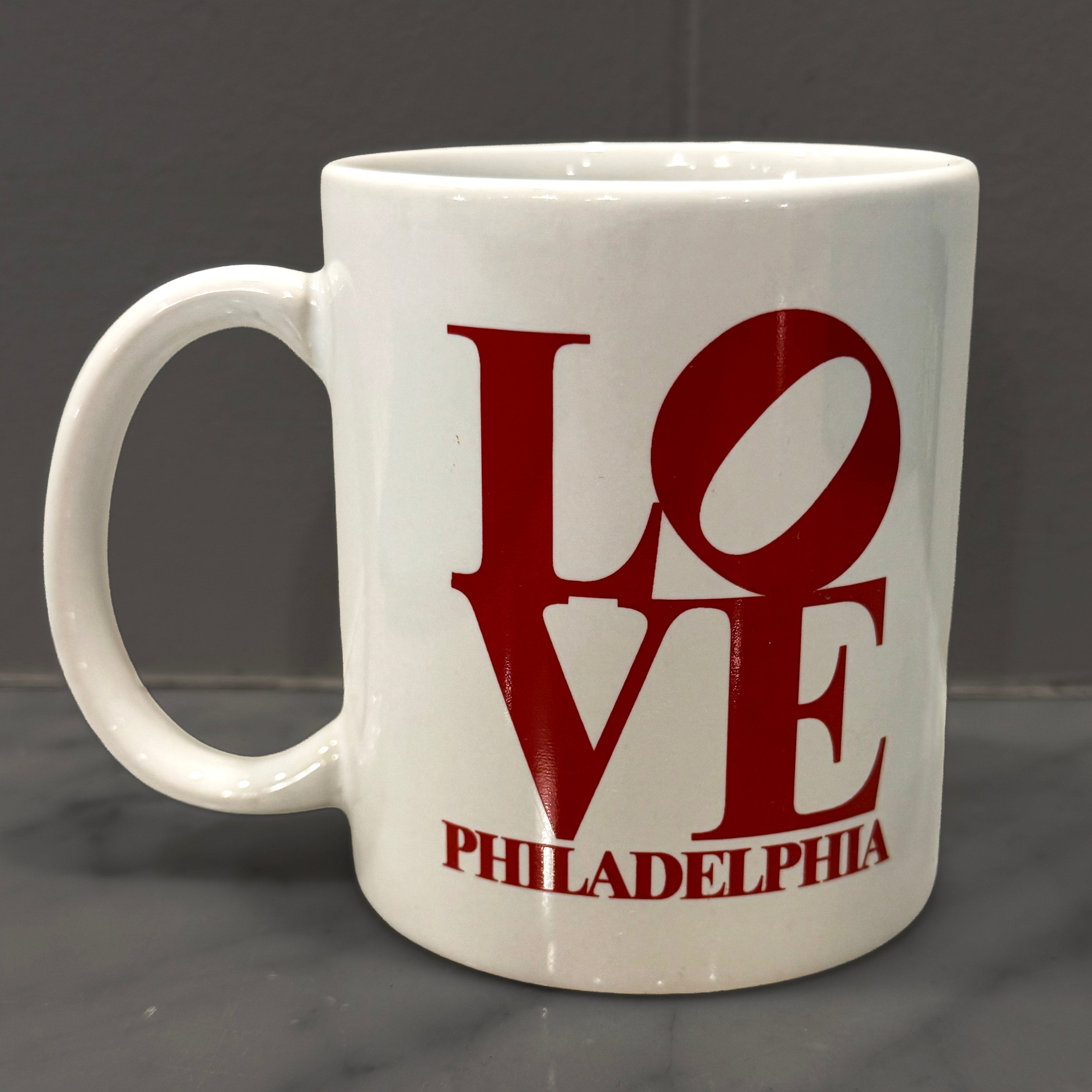 White mug with red 'LOVE Philadelphia' text on a dark background