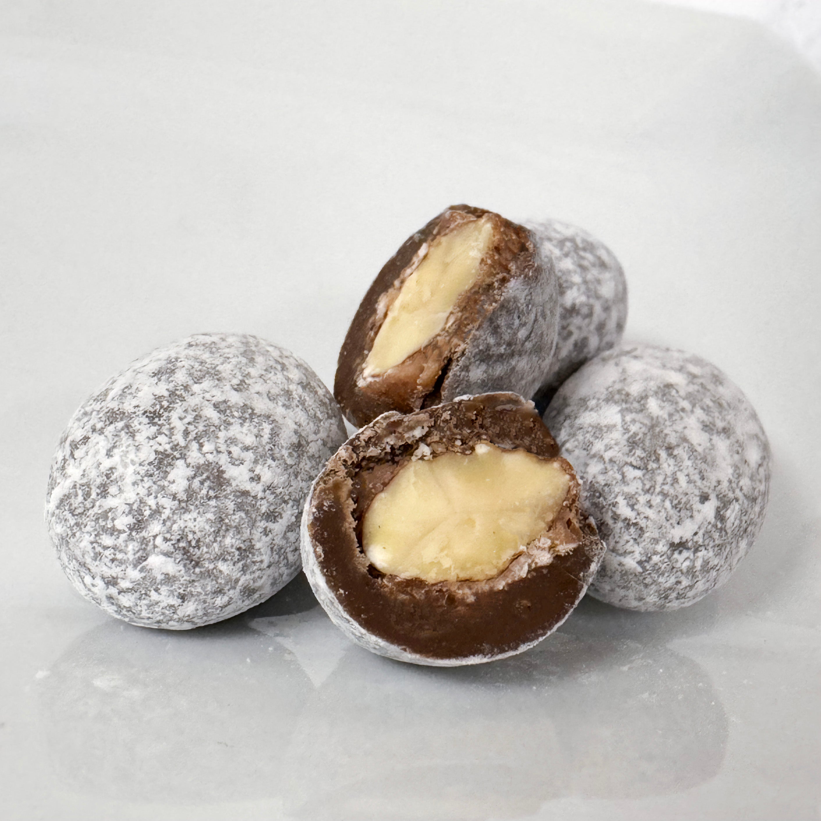 Chocolate toffee with a whole roasted almond center on a white surface