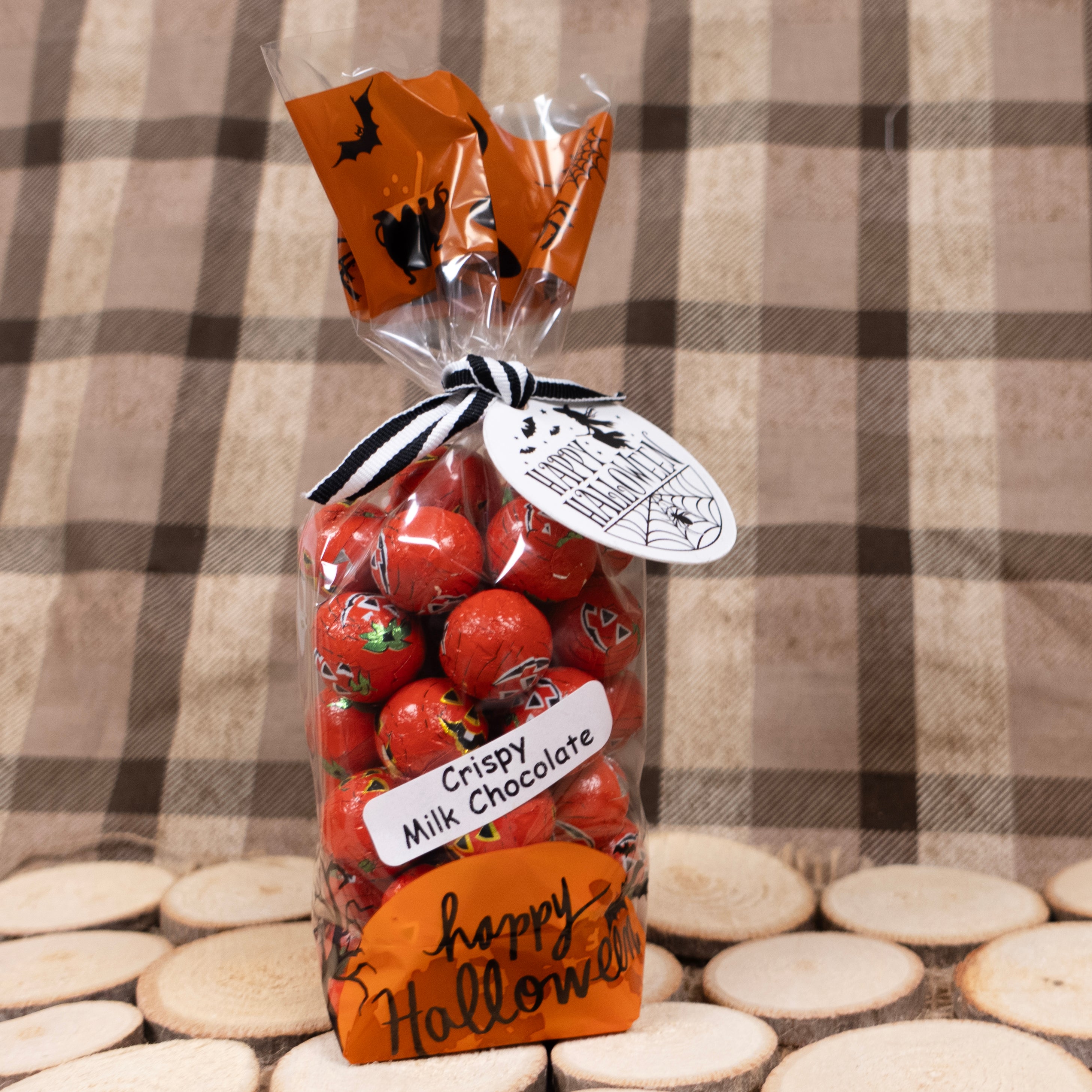 Bag of foiled Crispy Milk Chocolates with Halloween-themed packaging on a brown flannel checkered background
