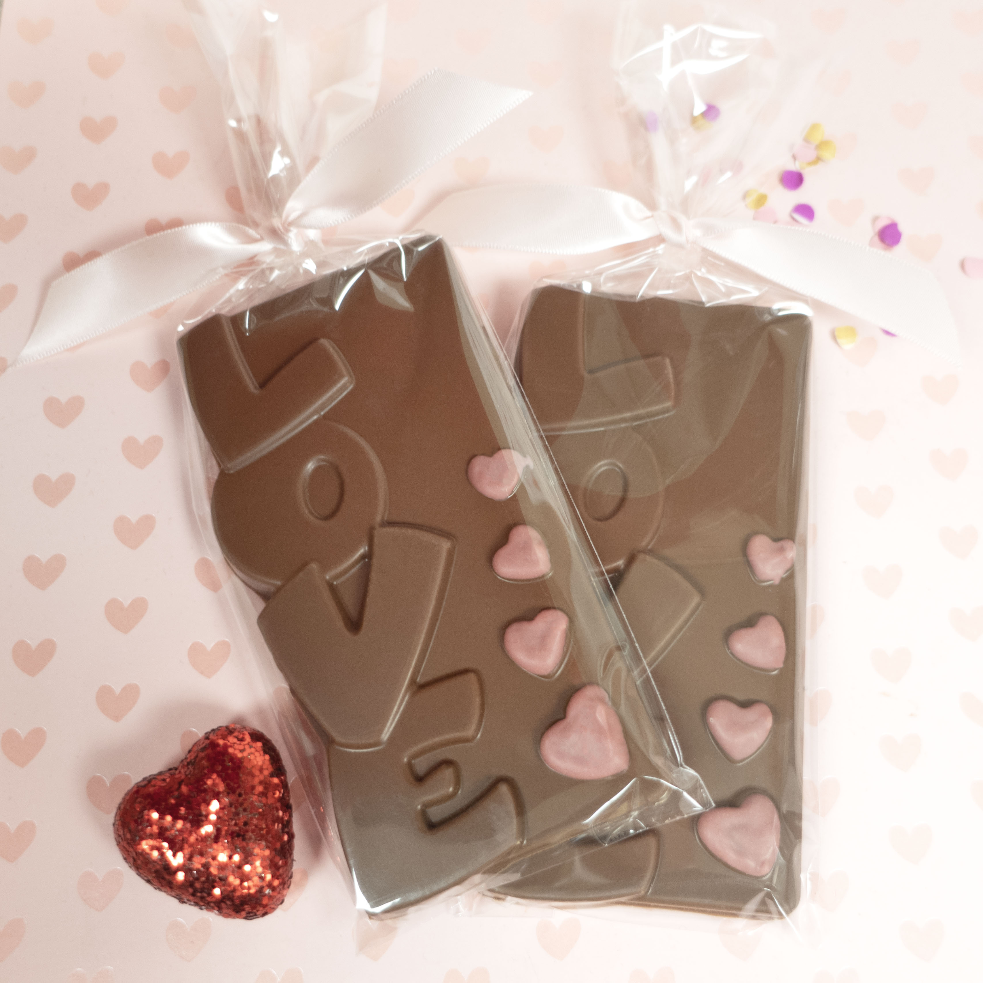 Lore's Chocolate mold shaped like the word 'LOVE' with pink ruby chocolate hearts on a heart-patterned background.