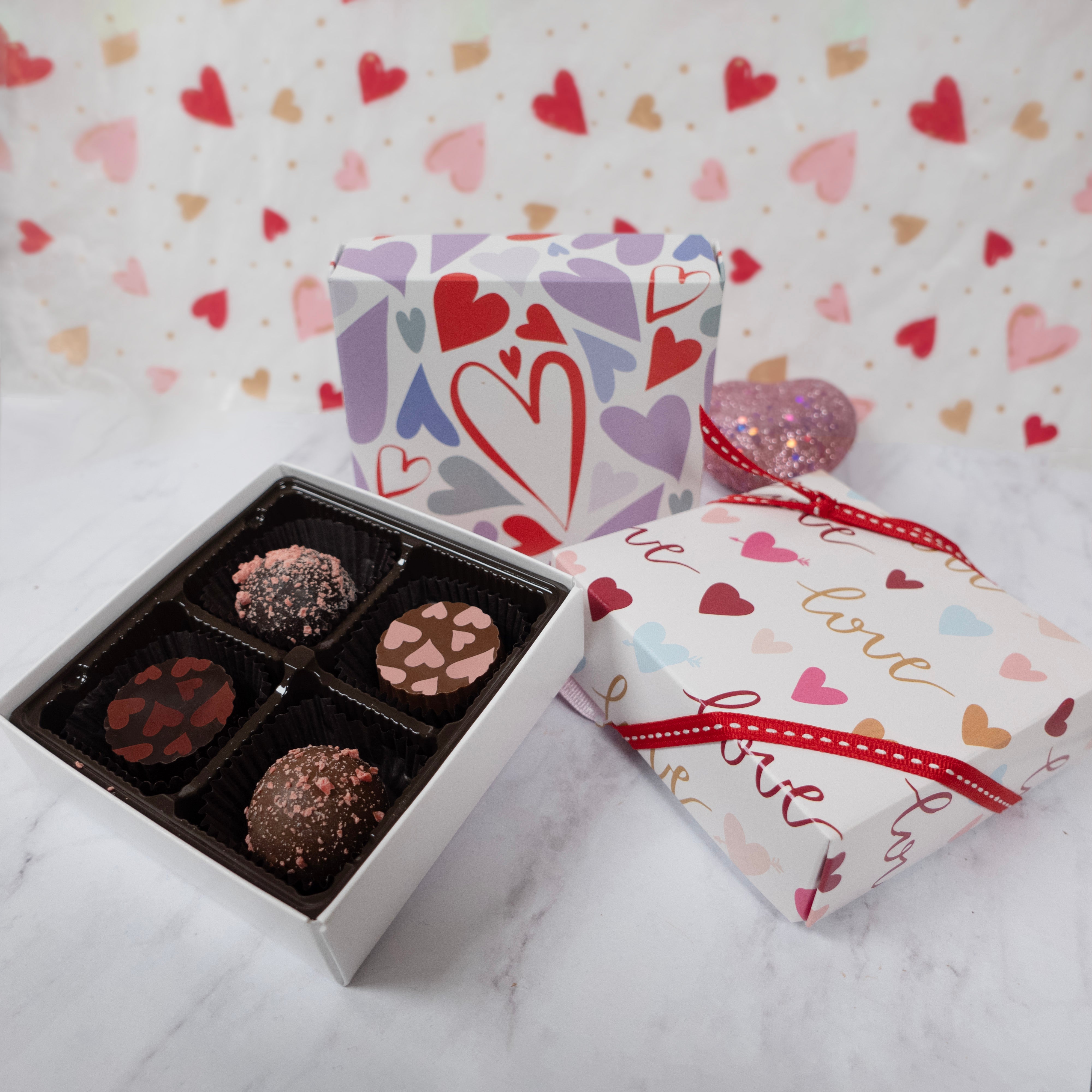 Box of chocolates with a decorative heart-themed box and a heart-patterned background.