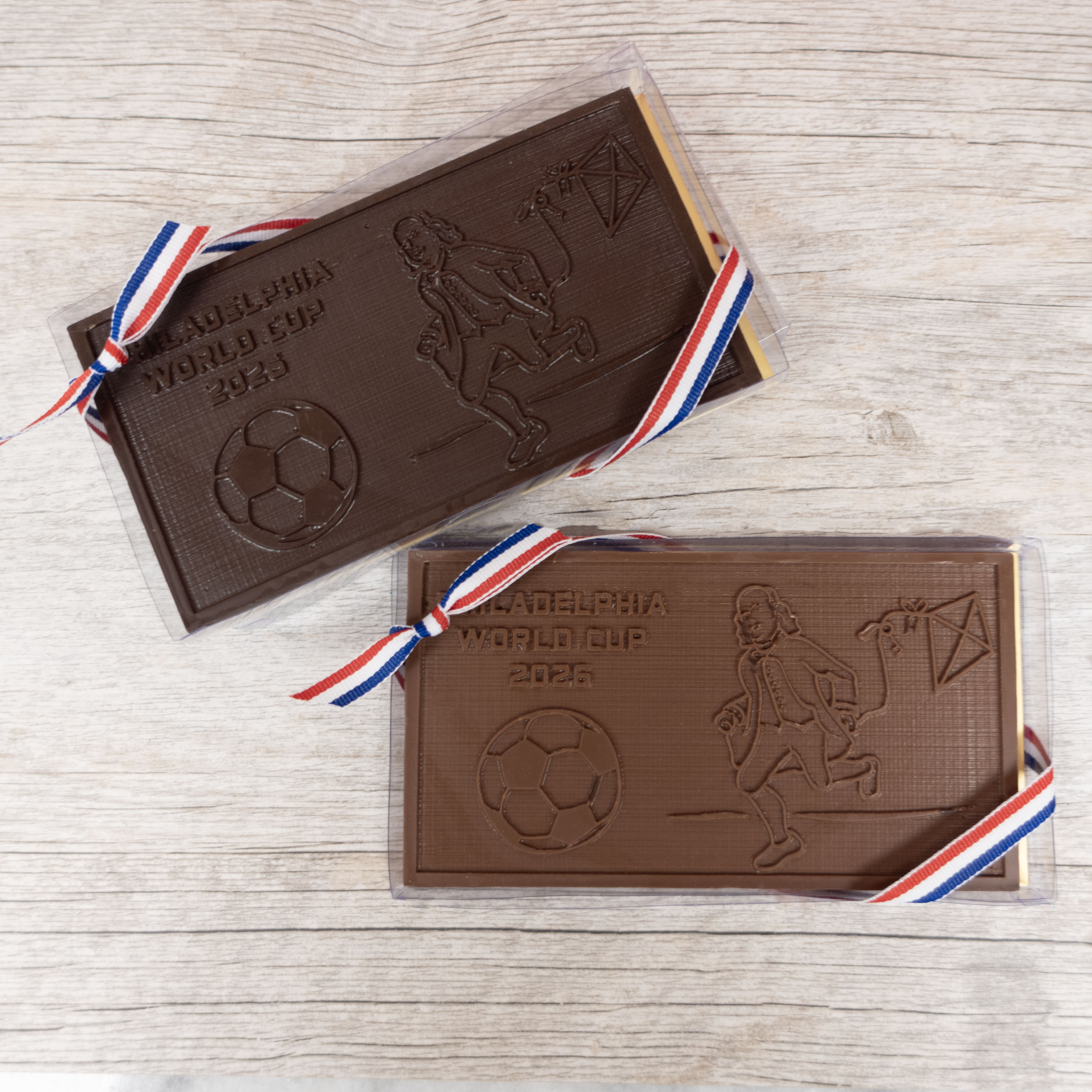 Two chocolate bars with soccer-themed designs for FIFA world cup on a wooden surface