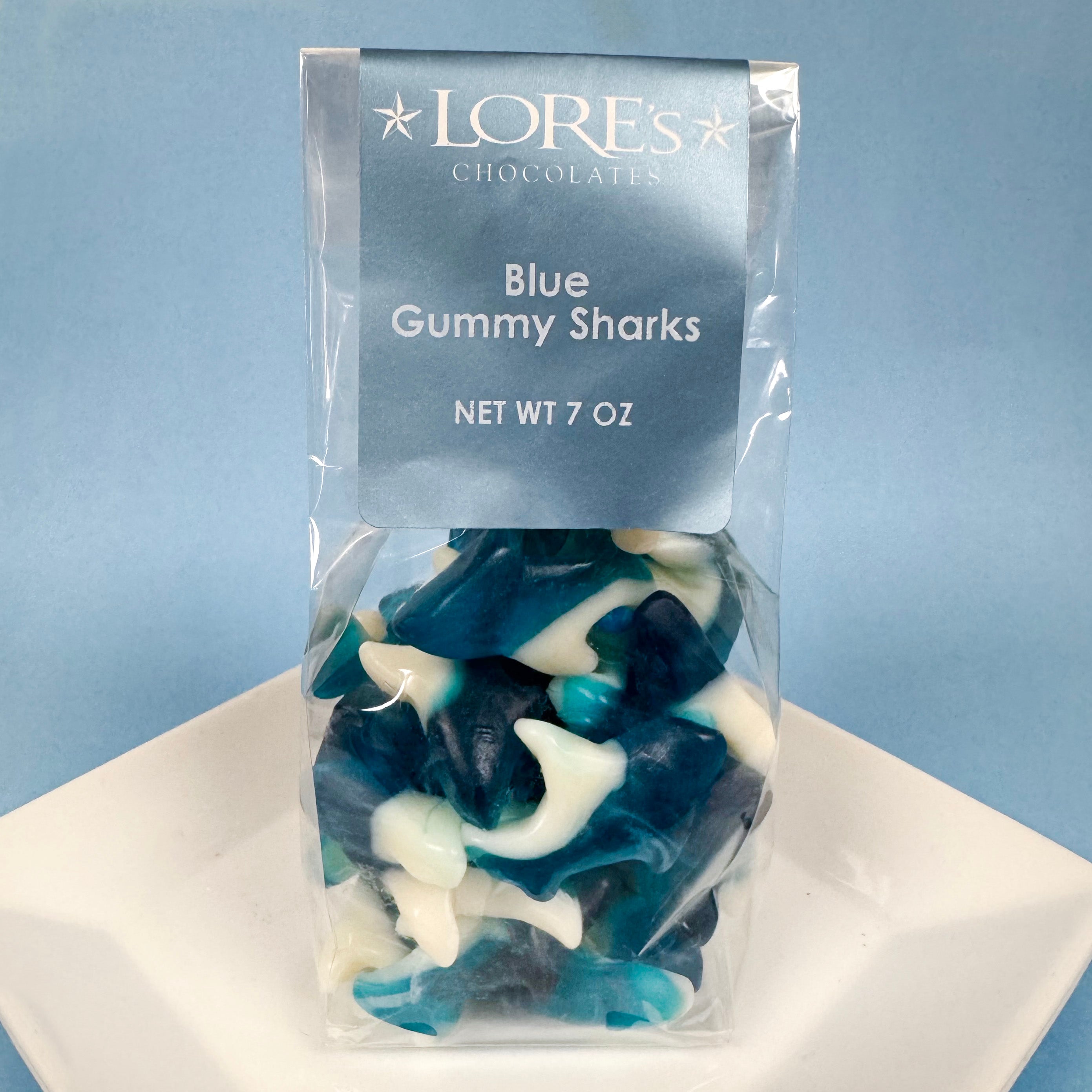 Packaged blue gummy sharks with LORE's CHOCOLATES branding on a light blue background