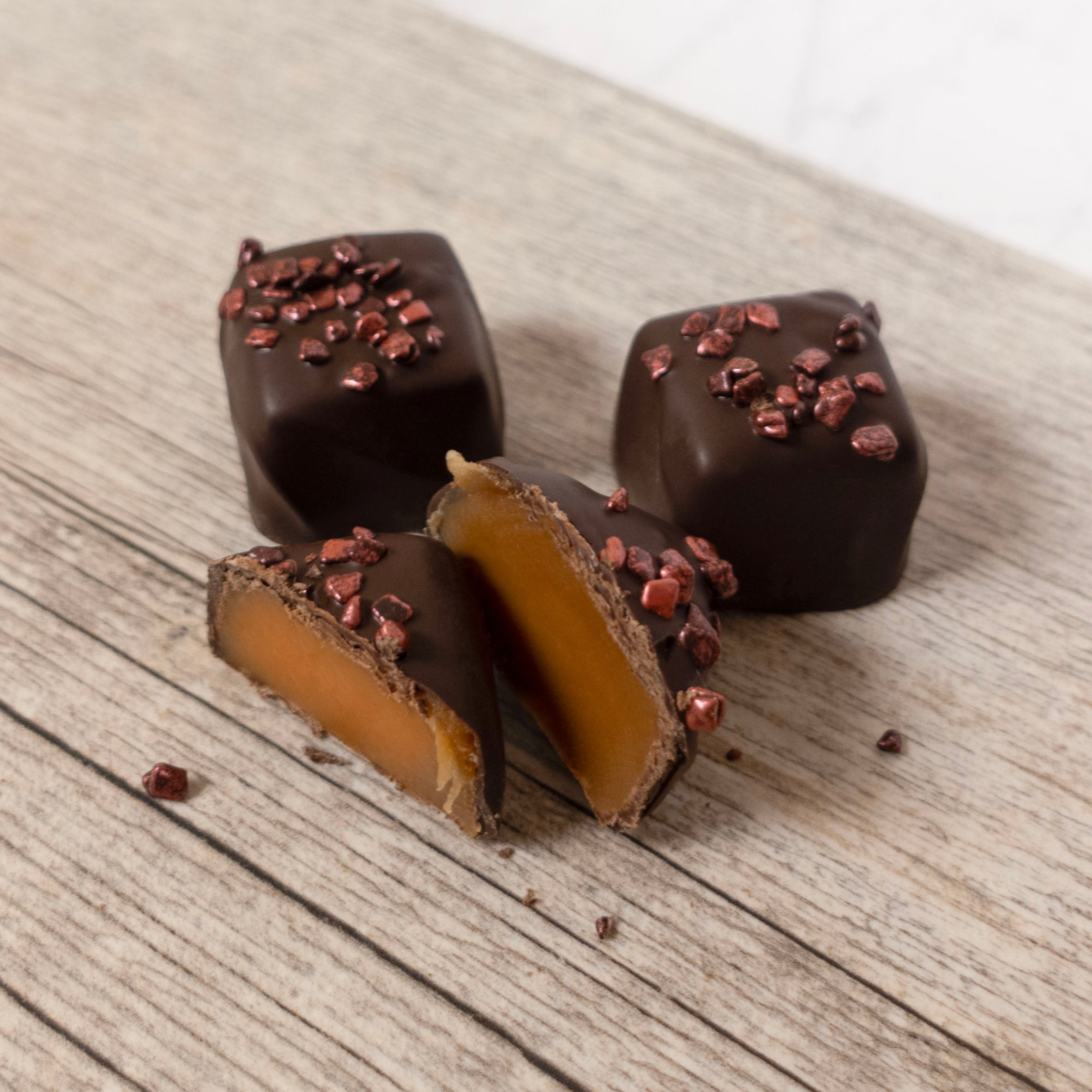Lore's Dark Chocolates with a caramel center on a wooden surface