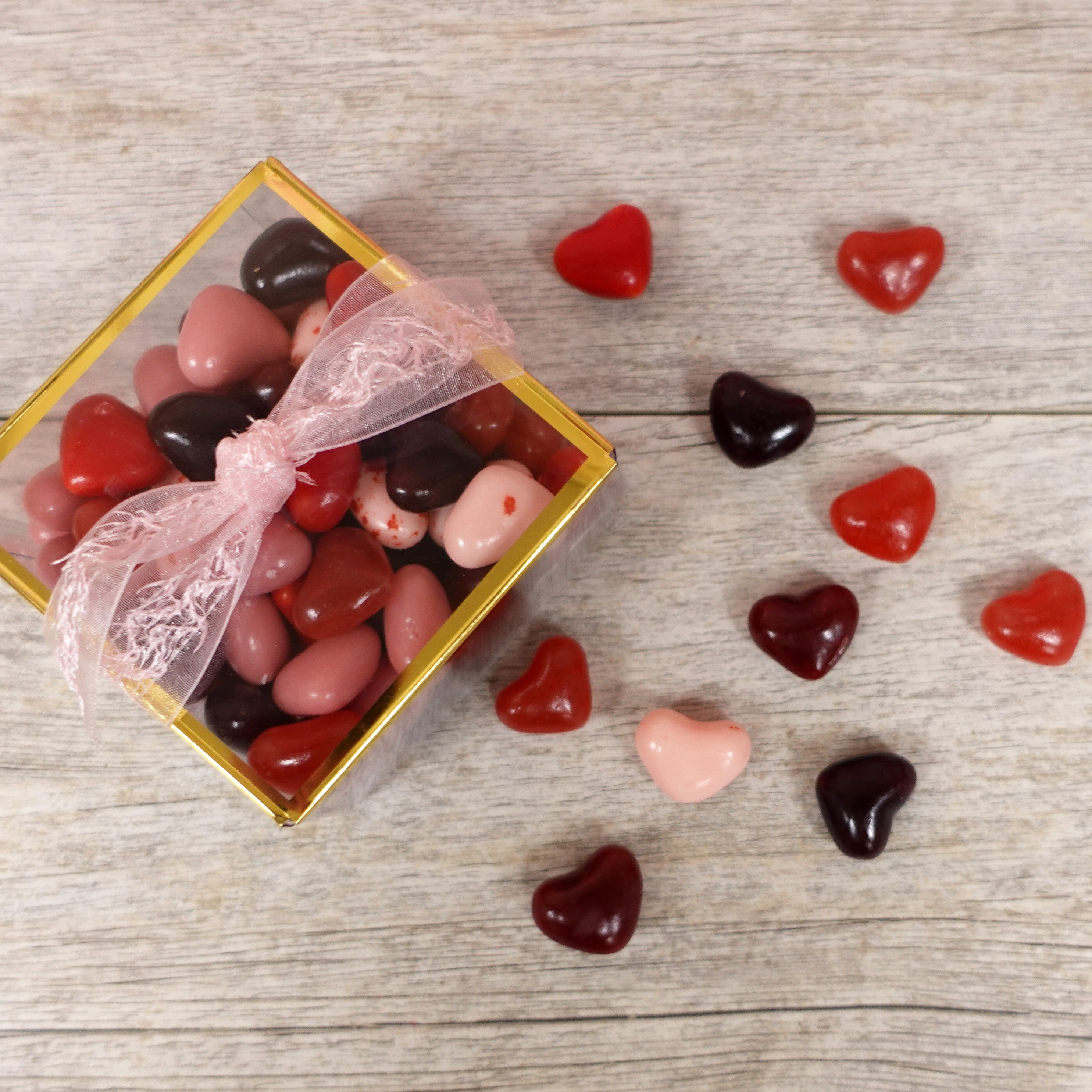 heart shaped jelly beans in various cherry flavors and different pink and red colors for valentine's day. packaged in a clear box with gold accent and lacey pink ribbon - sold at lore's chocolates in philadelphia