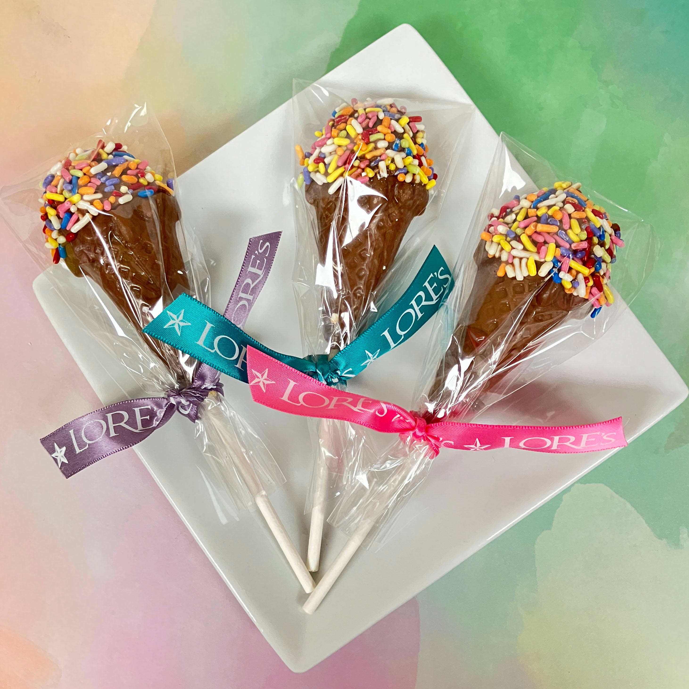 Lore's Chocolates milk chocolate lollipops shaped like ice cream cones with jimmies aka sprinkles. packaged in cellophane with assorted Lore's ribbon