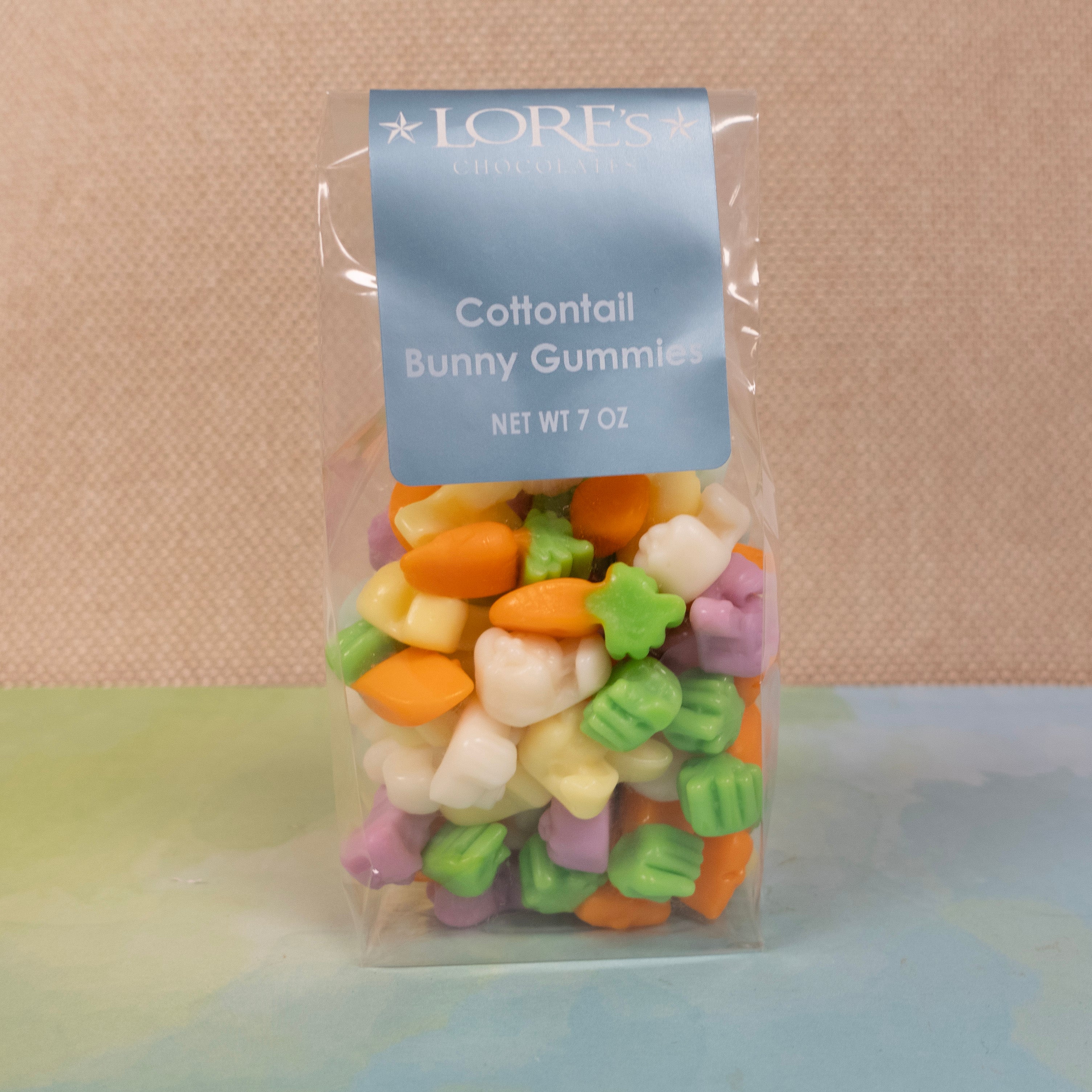 Gummy Bunnies is various pastel colors and carrot shapped gummies - bagged - label reads "Lore's Chocolates, Cottontail Bunny Gummies, Net Wt 7 oz"