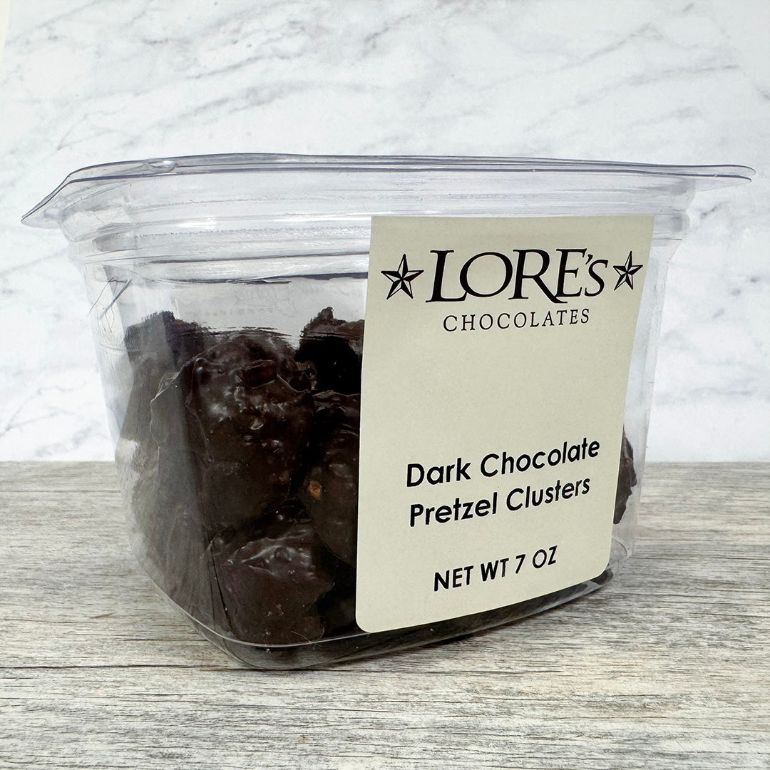 Container of dark chocolate pretzel clusters with a Lore's Chocolates label on a marble surface.