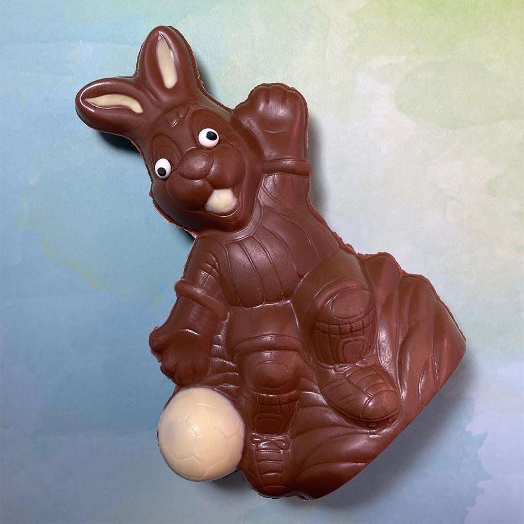Chocolate Easter bunny with a white chocolate soccer ball on a gradient background