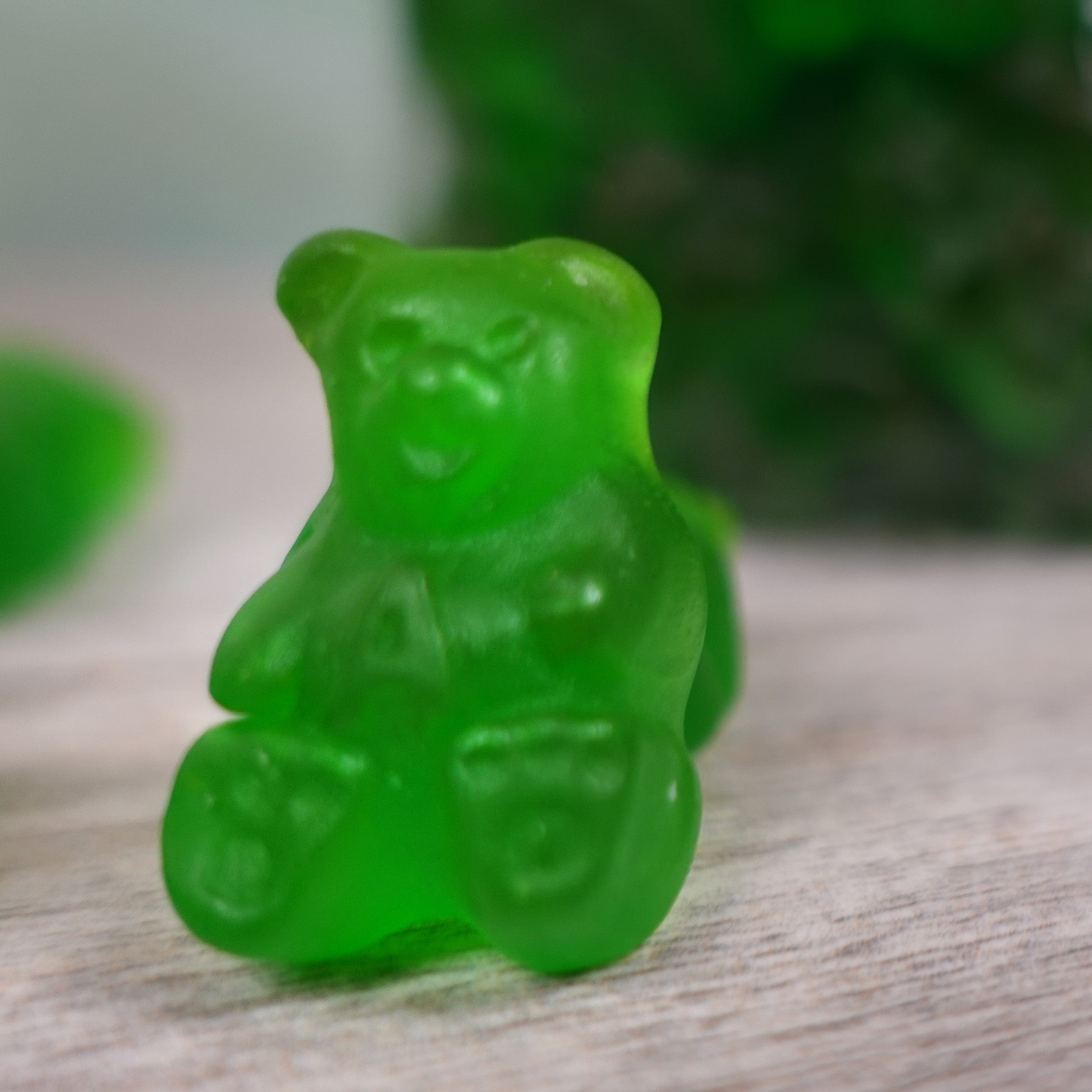 Close up of a green apple gummy bear with an A on its chest 