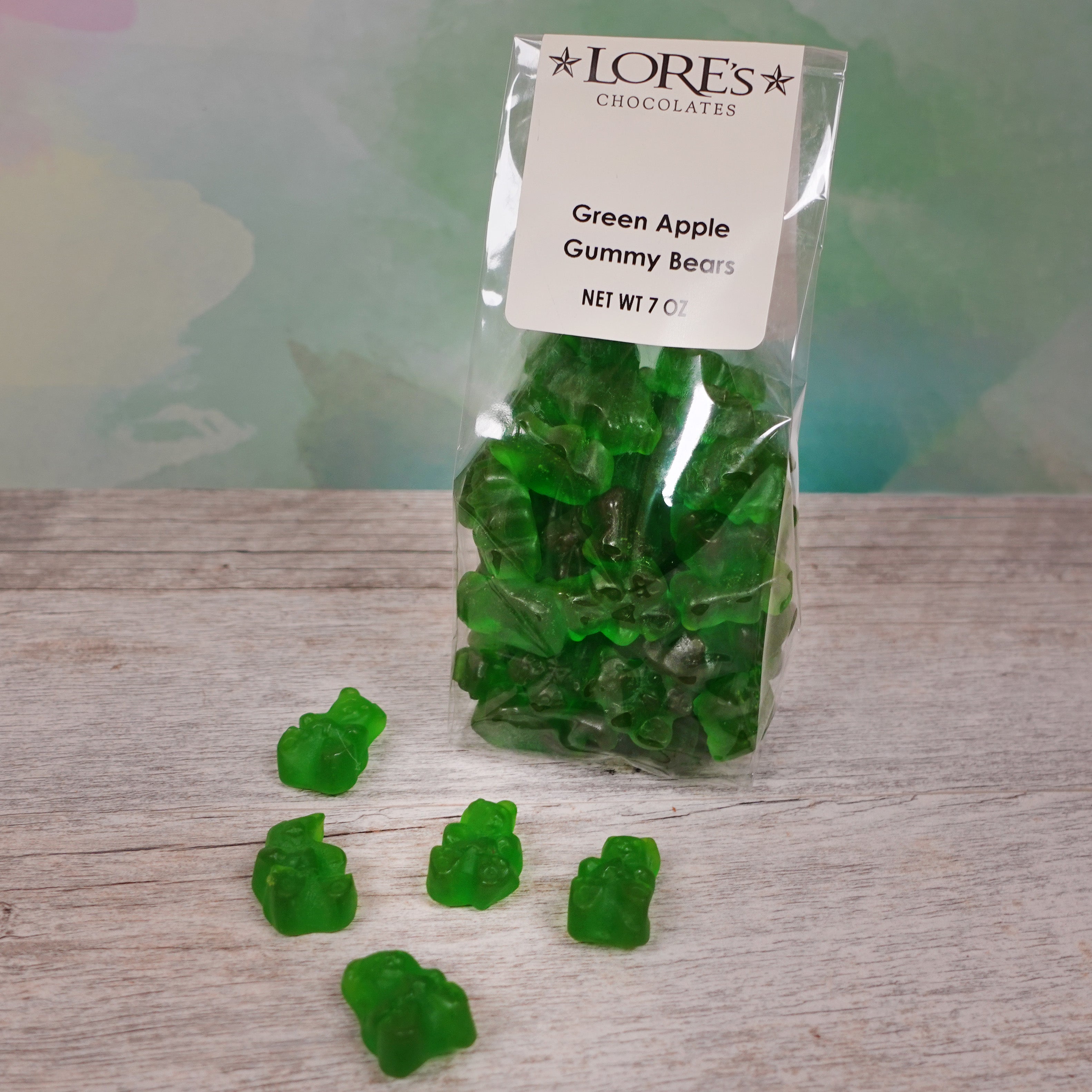 Bright green gummy bears with Green Apple Flavor packaged in clear bag - cream-colored label reads "Lore's Chocolates, Green Apple, Gummy Bears, Net Wt 7 oz" 