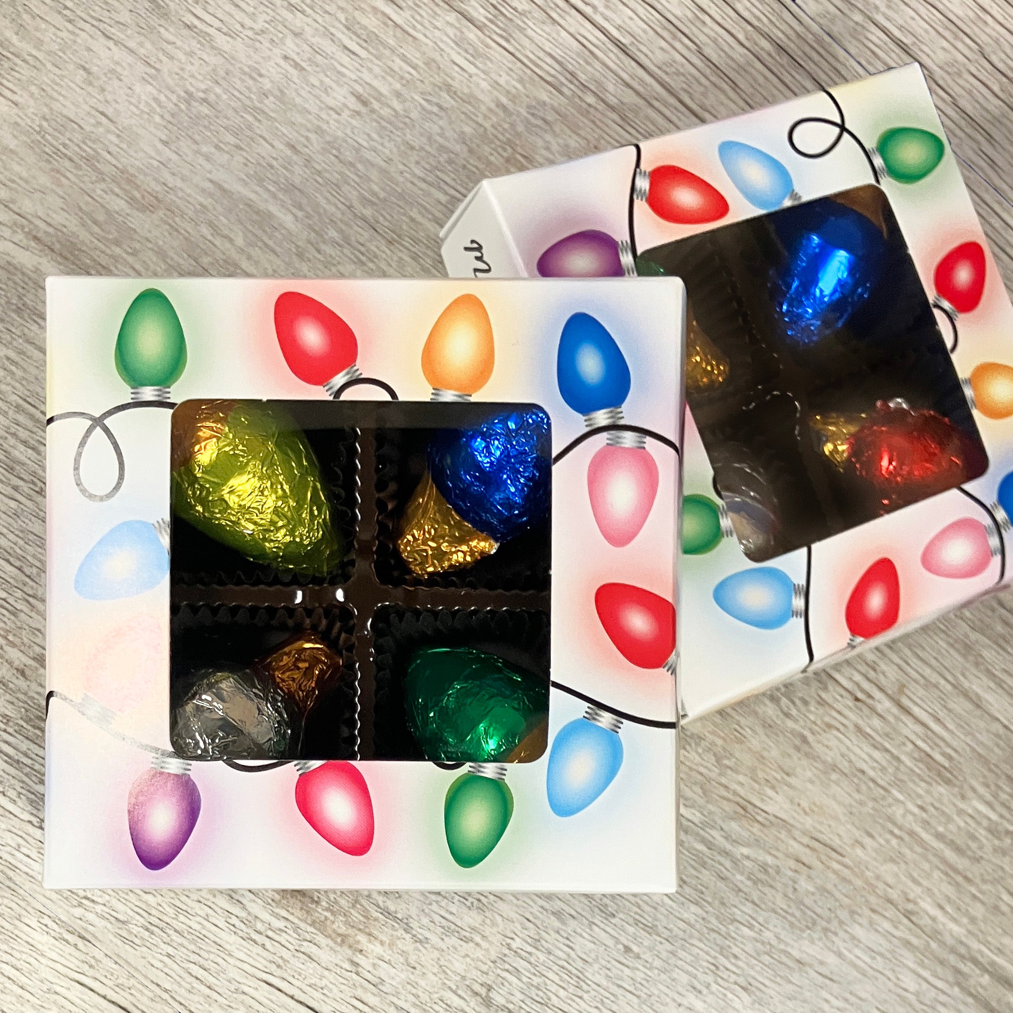 Box of assorted chocolates with a festive design on a wooden surface