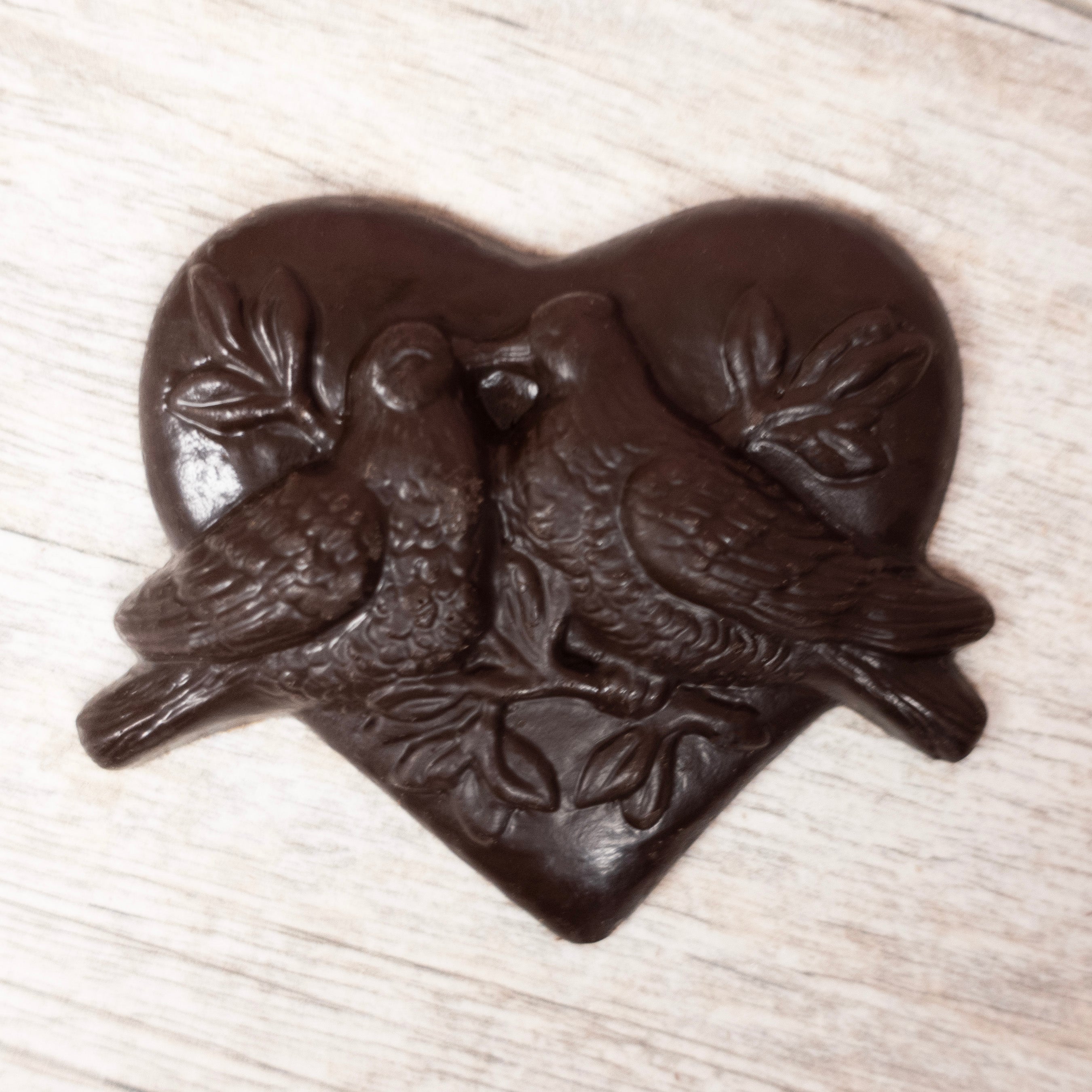 solid chocolate mold: lovebirds kissing on a branch, surrounded by a heart in Lore's Dark chocolate. 