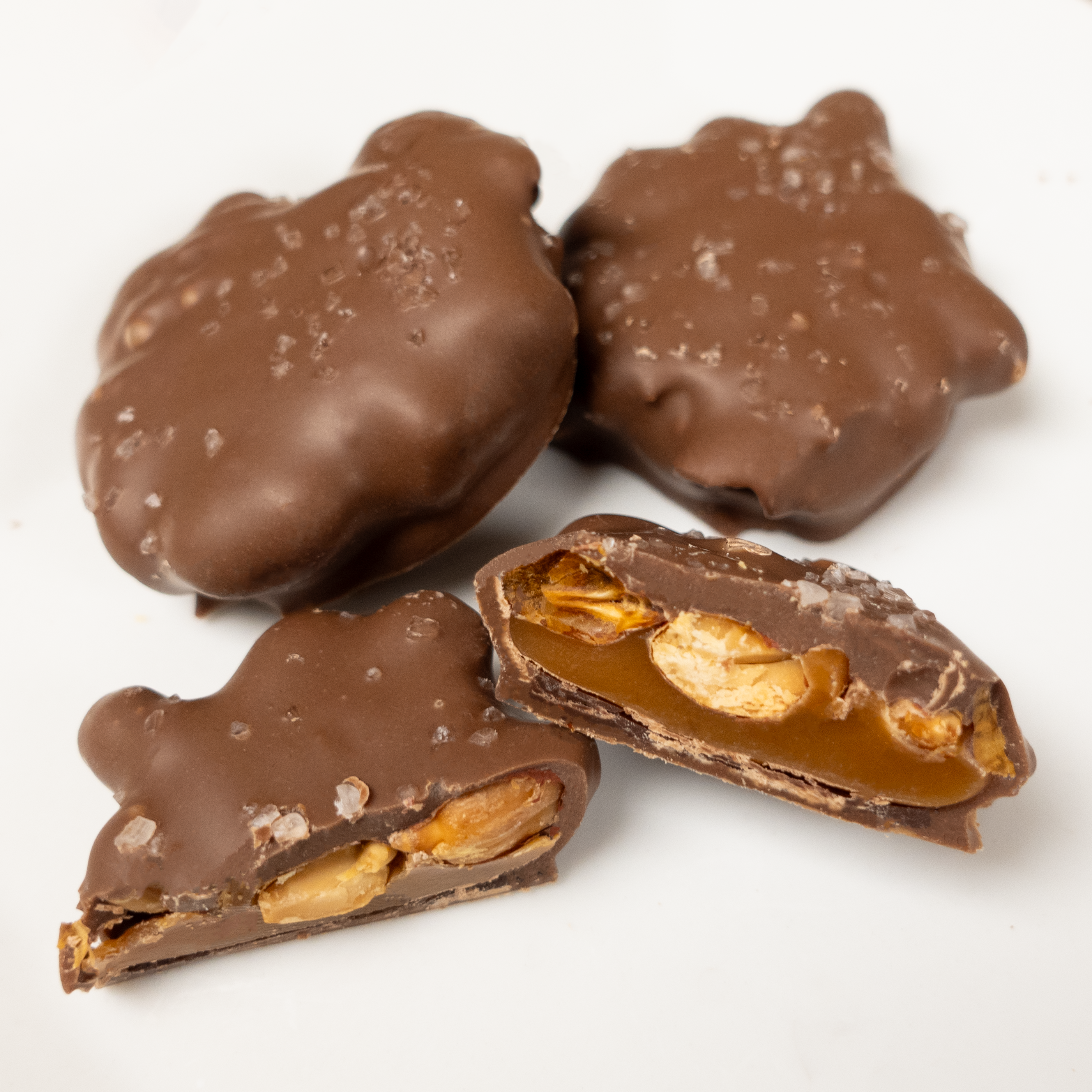 Milk Chocolate patties with centers showing roasted peanuts and caramel, topped with flaky sea salt