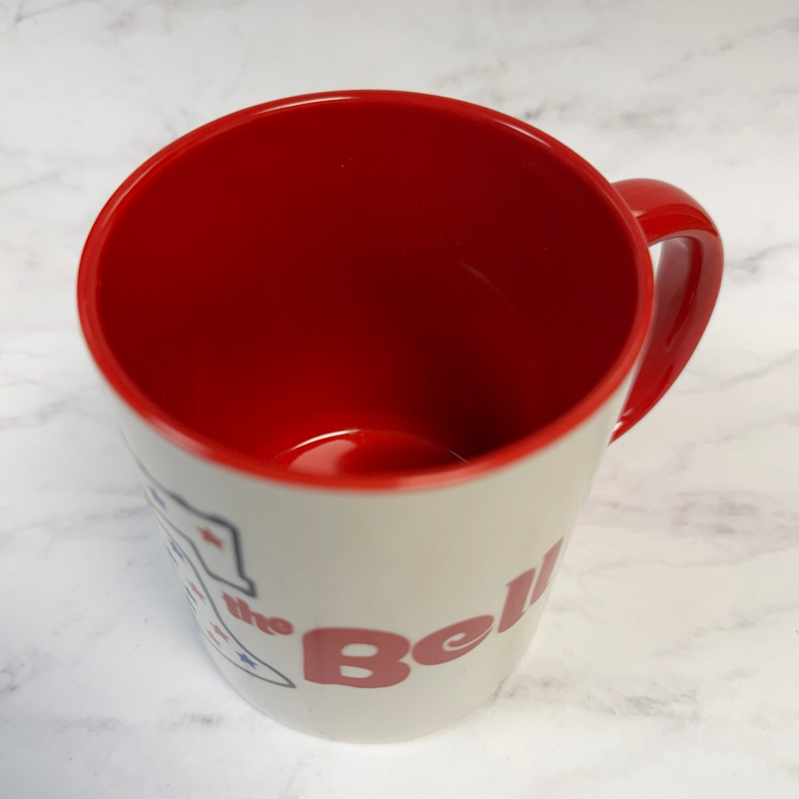 Red and white mug with 'Ring the The Bell' branding on a white marble surface - image shows this philly mug top down to show the interior